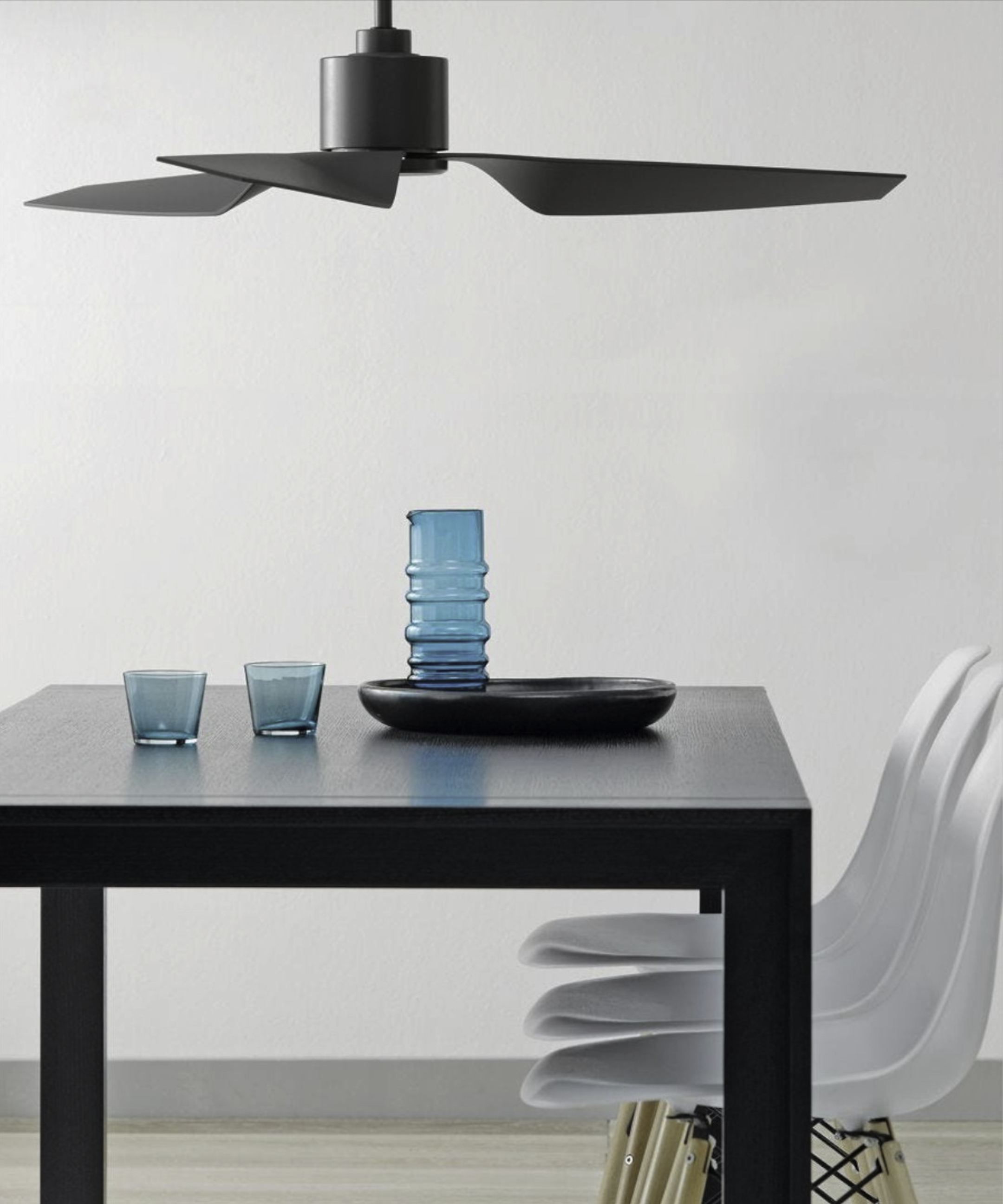 Moderner Esstisch mit blauem Glas und schwarzem Deckenventilator.