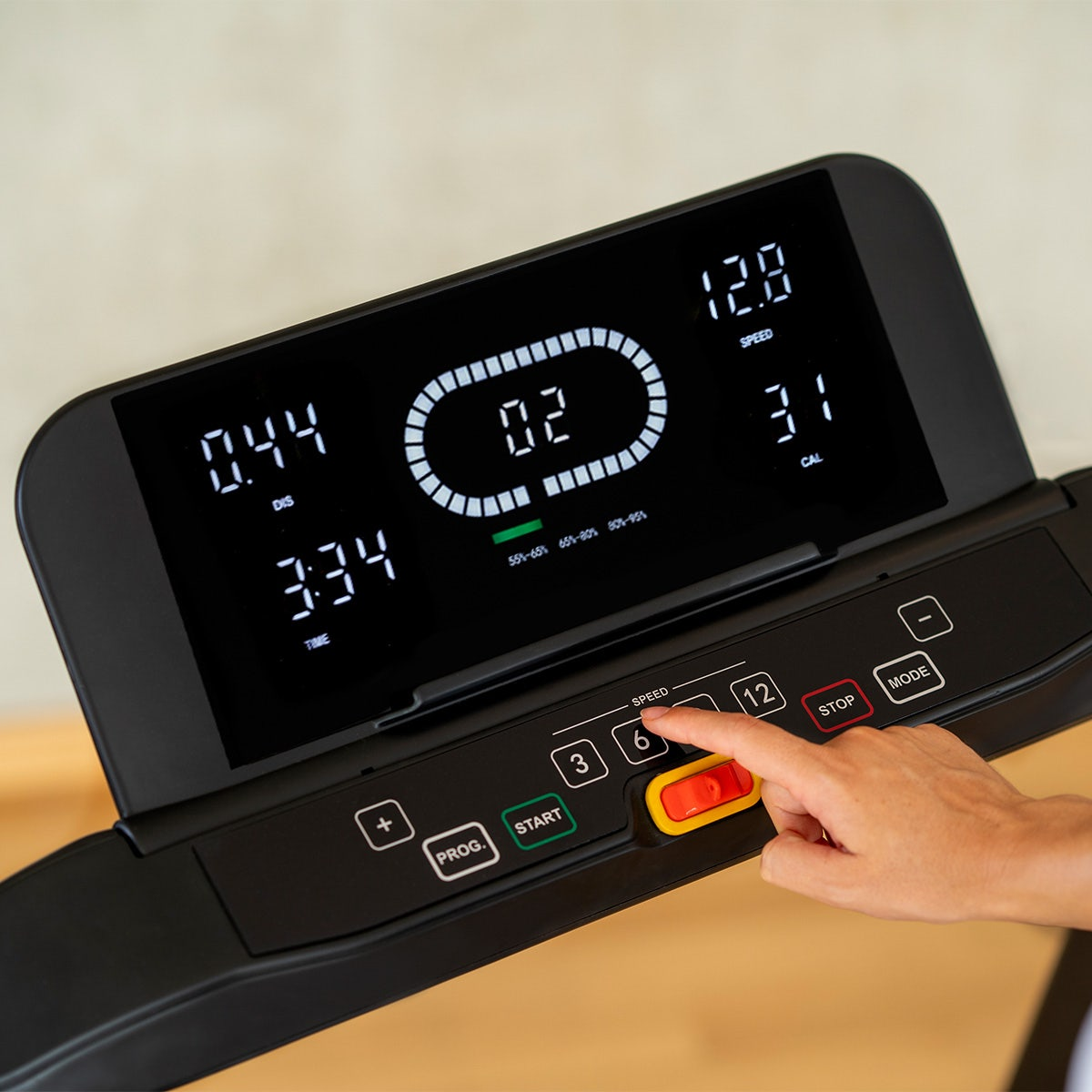 Laufband-Bedienfeld mit Anzeige, Hand berührt Geschwindigkeitstaste.