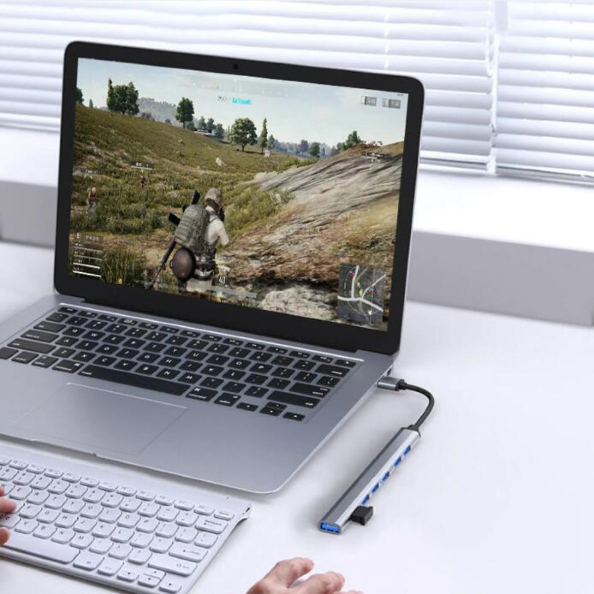 Laptop mit angeschlossenem Hub. Der Bildschirm zeigt eine Videospielszene.