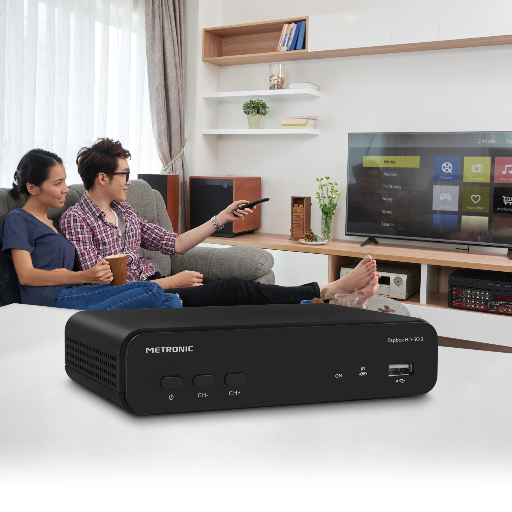Una pareja viendo la televisión en el salón. Una caja METRONIC negra está delante del televisor.