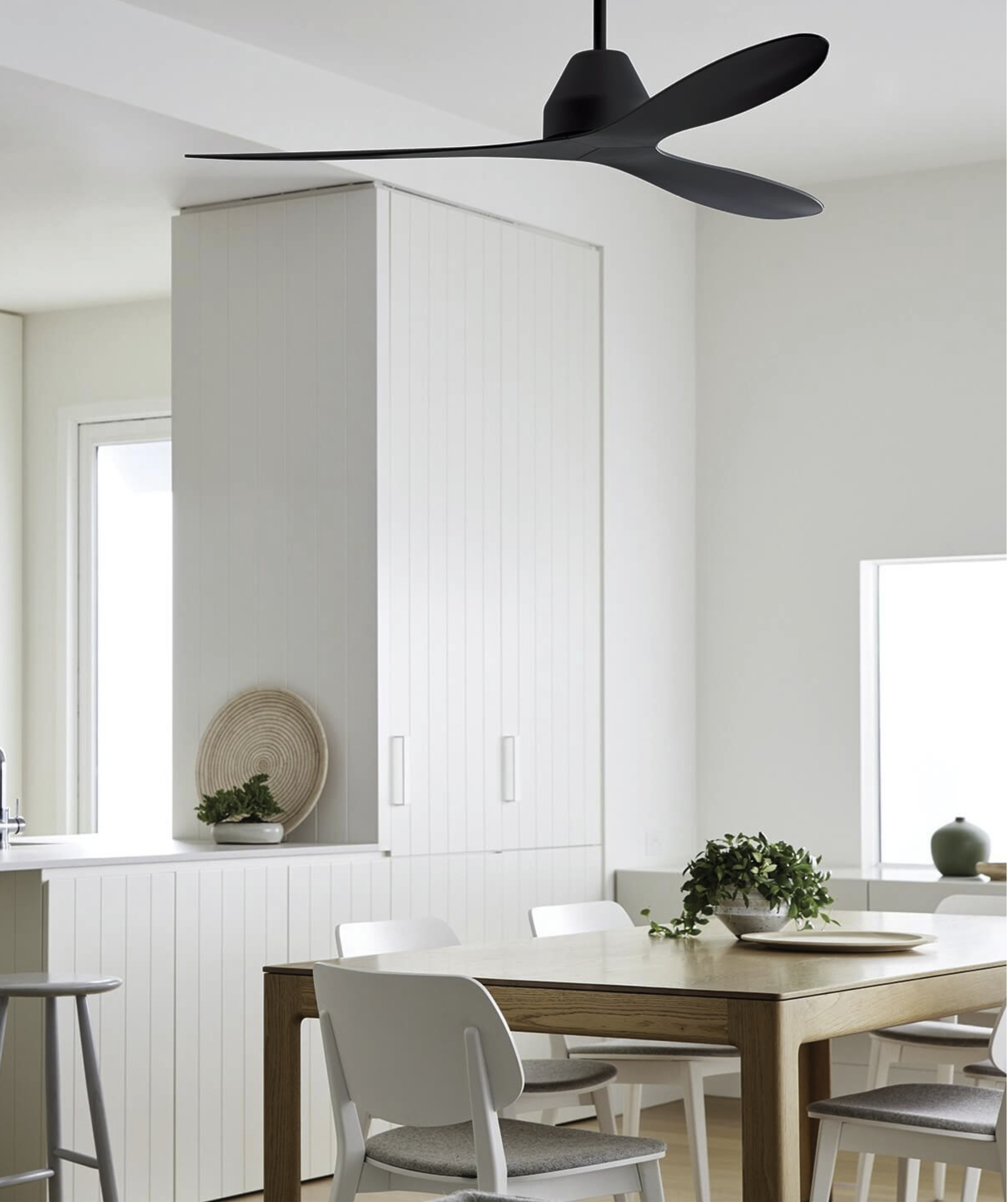 Ein modernes Esszimmer mit schwarzem Deckenventilator und weißen Möbeln.