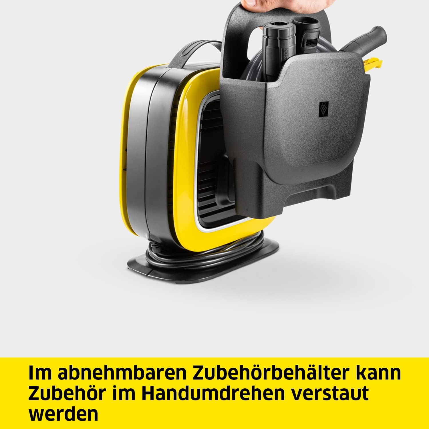 Gelb-schwarze Pumpe mit Griff und Zubehörhalter. Eine Hand hält den Zubehörhalter.