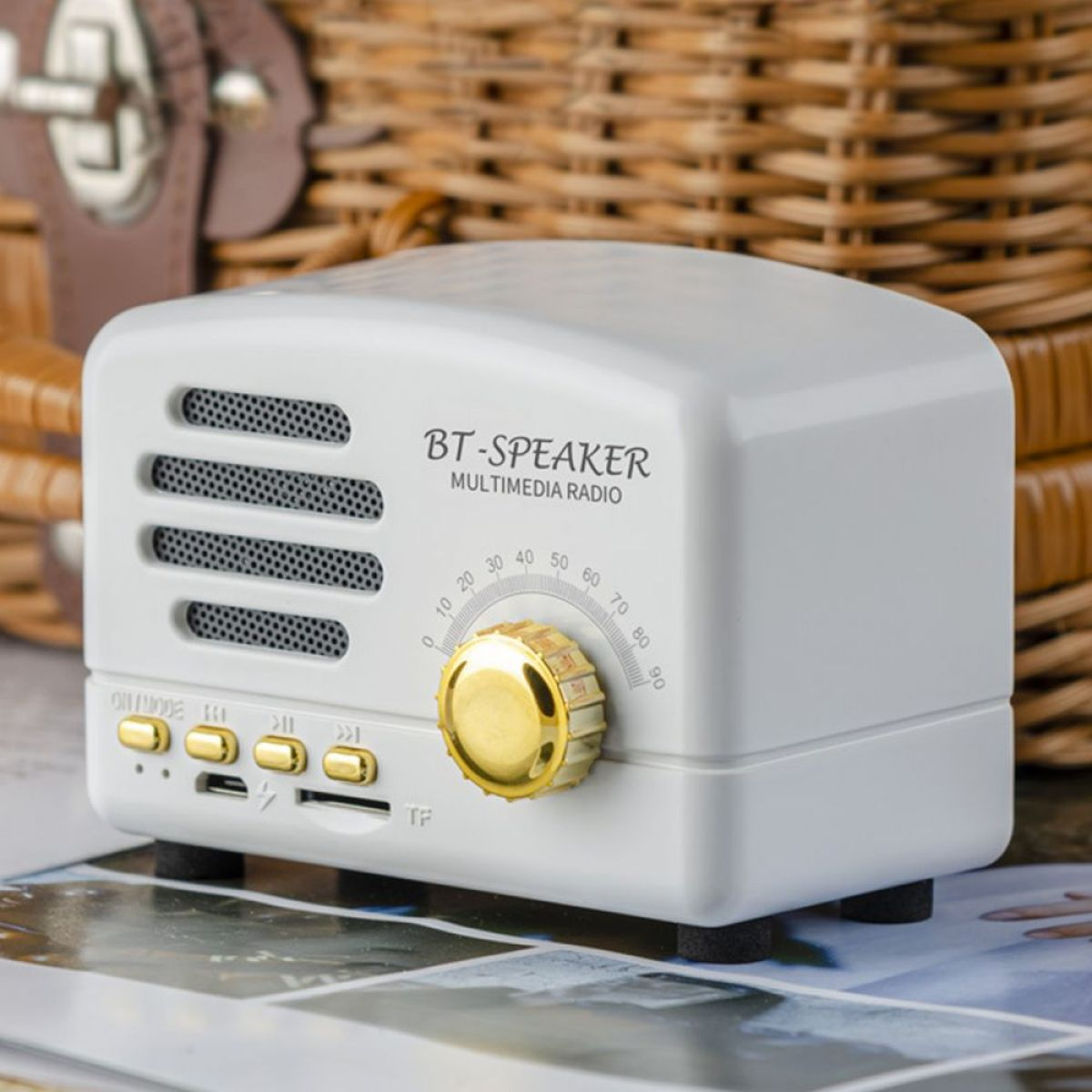 Ein weißer BT-Lautsprecher im Retro-Stil mit goldenem Drehknopf und Tasten.