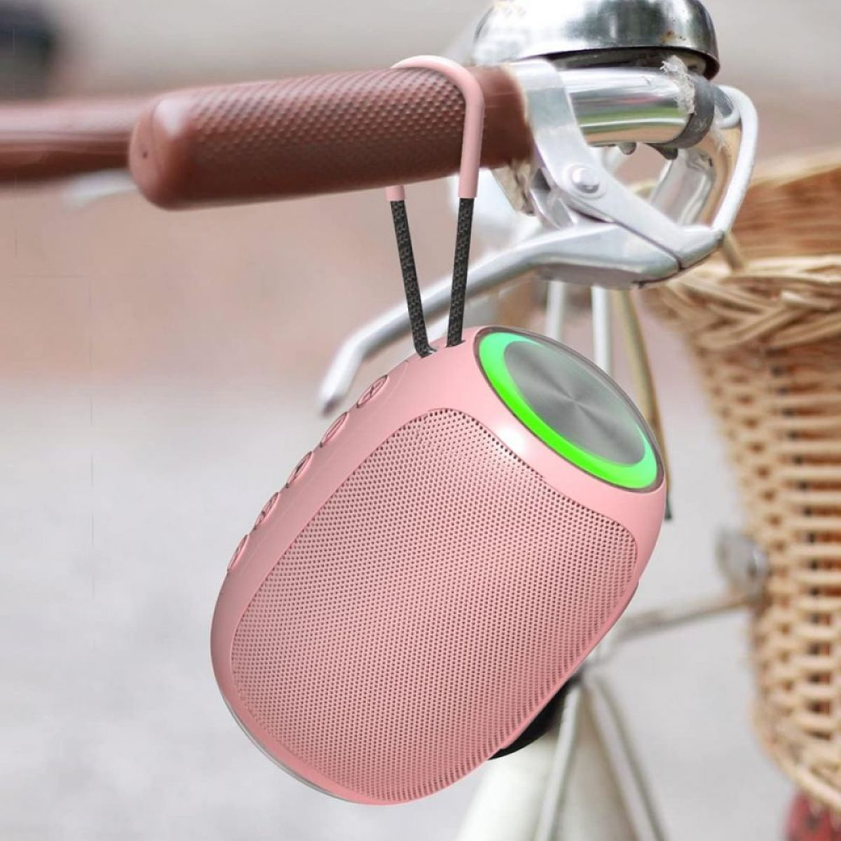 Ein rosa Lautsprecher hängt am Lenker eines Fahrrads. Der Lautsprecher hat ein grünes Licht und Knöpfe.