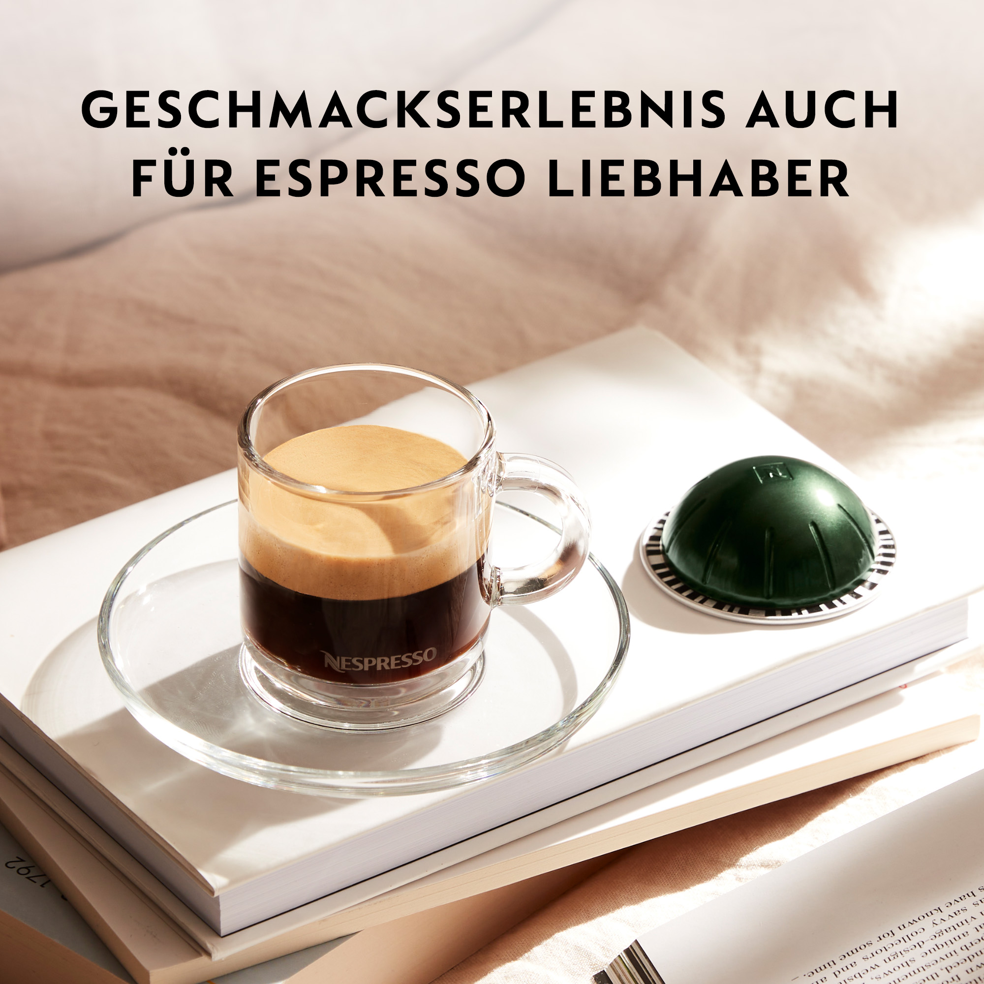 Ein Glas Espresso auf einer weißen Untertasse, neben einer grünen Kaffeekapsel auf Büchern.