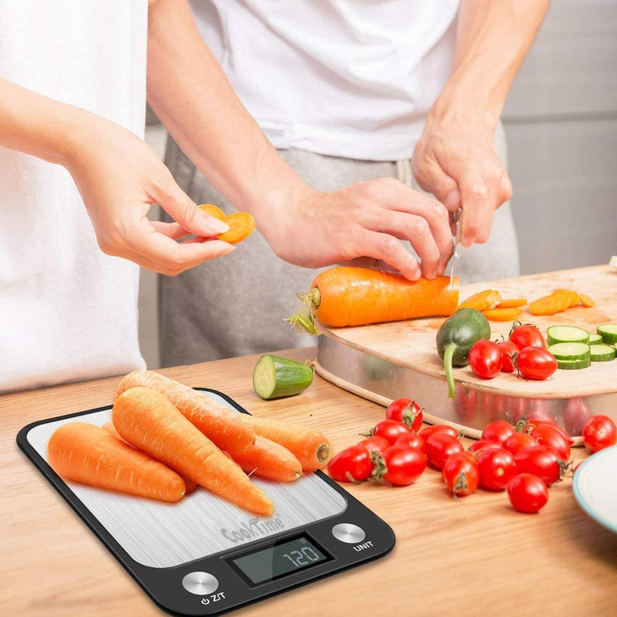 Personen schneiden Karotten und Tomaten auf einer Waage mit Karotten darauf.
