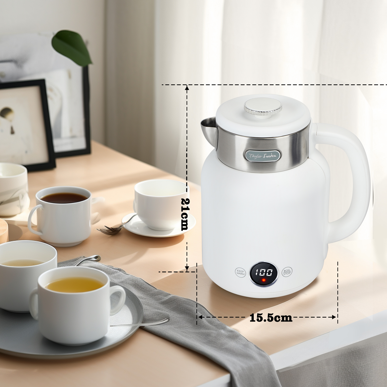 Una tetera eléctrica blanca con una pantalla digital, sobre una mesa de madera con tazas de té y una imagen enmarcada.
