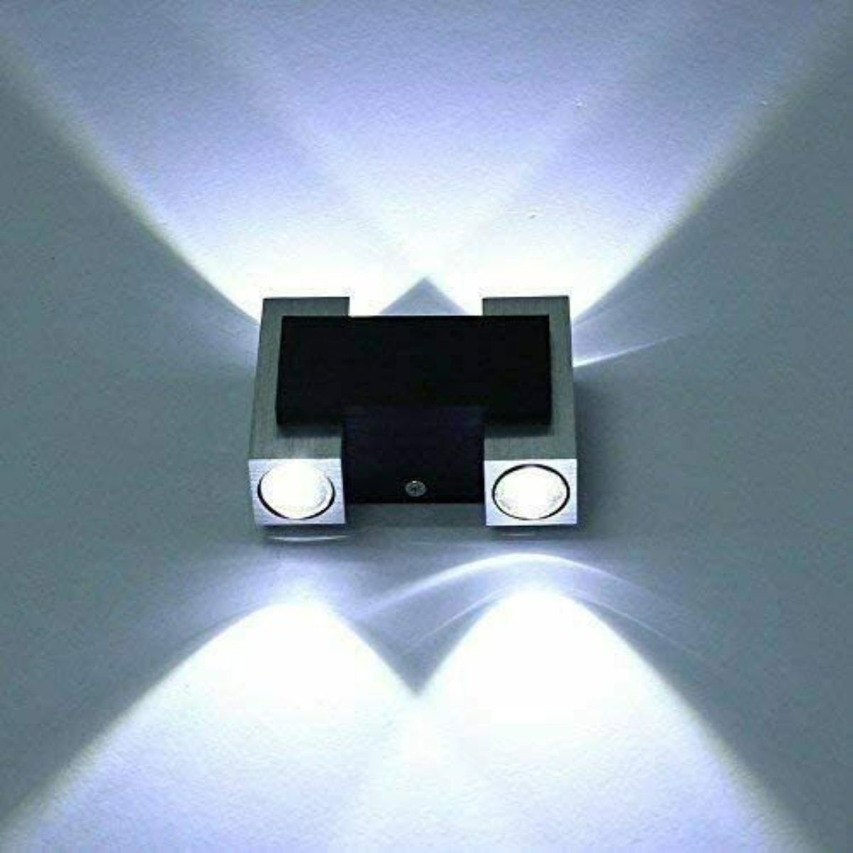 Moderne Wandleuchte, die zwei Lichtstrahlen aussendet, an einer hellgrauen Wand montiert.