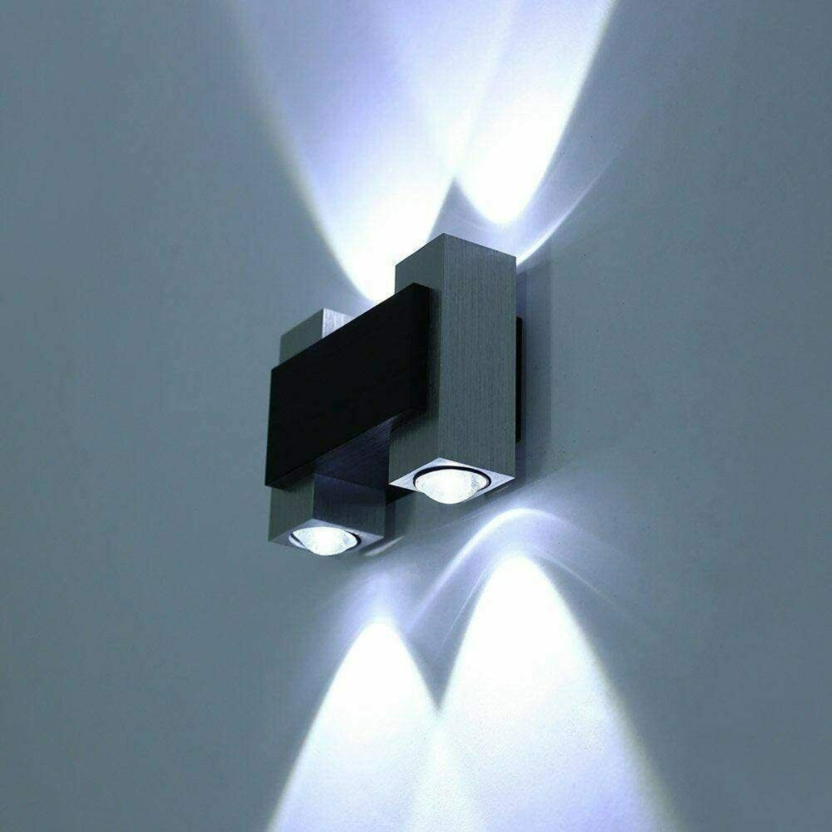 Moderne Wandleuchte mit zwei Lichtquellen. Sie hat einen silbernen Körper und schwarzen Akzent.