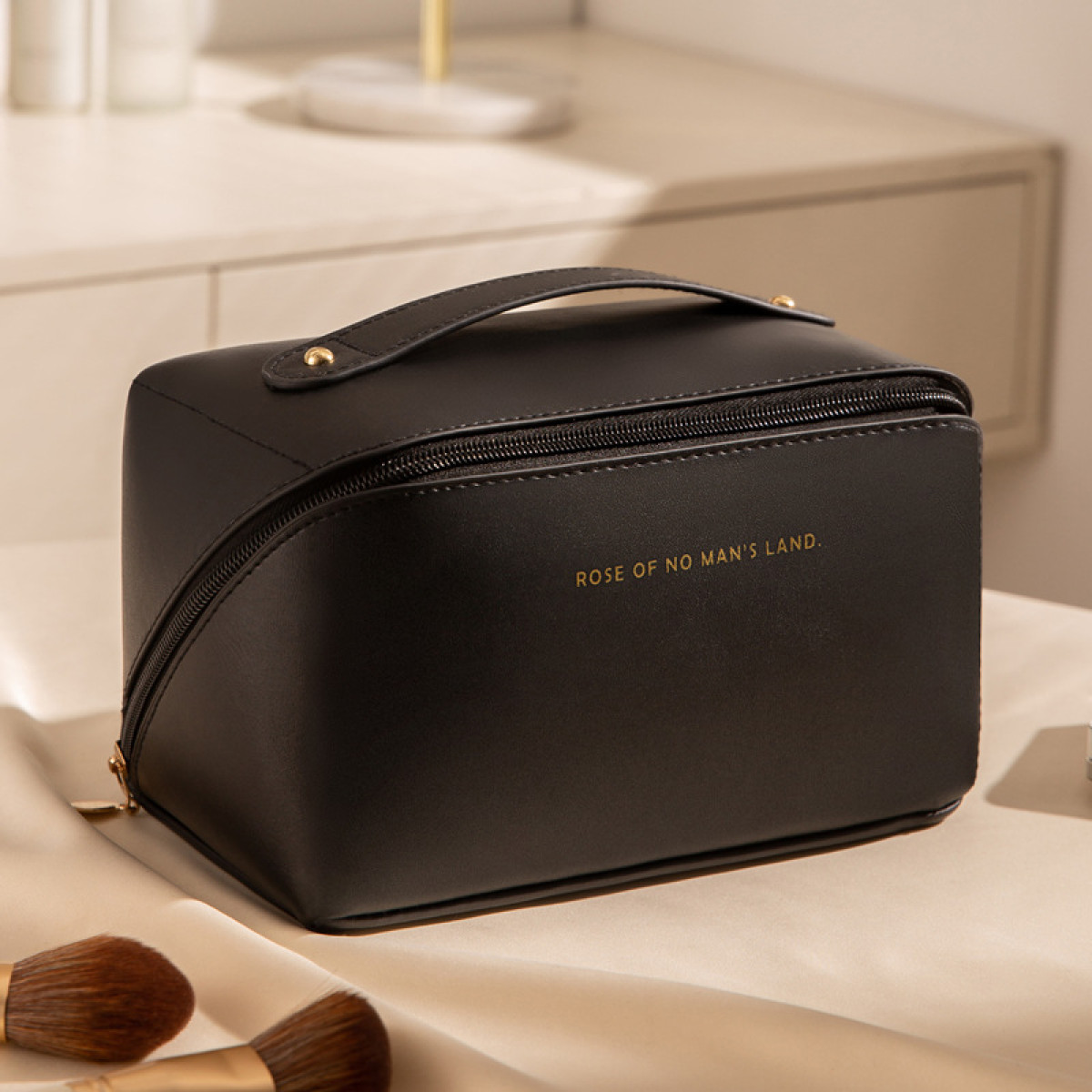 Schwarze Make-up-Tasche auf einem Tisch mit Pinseln. Text auf der Tasche: ROSE OF NO MAN'S LAND.