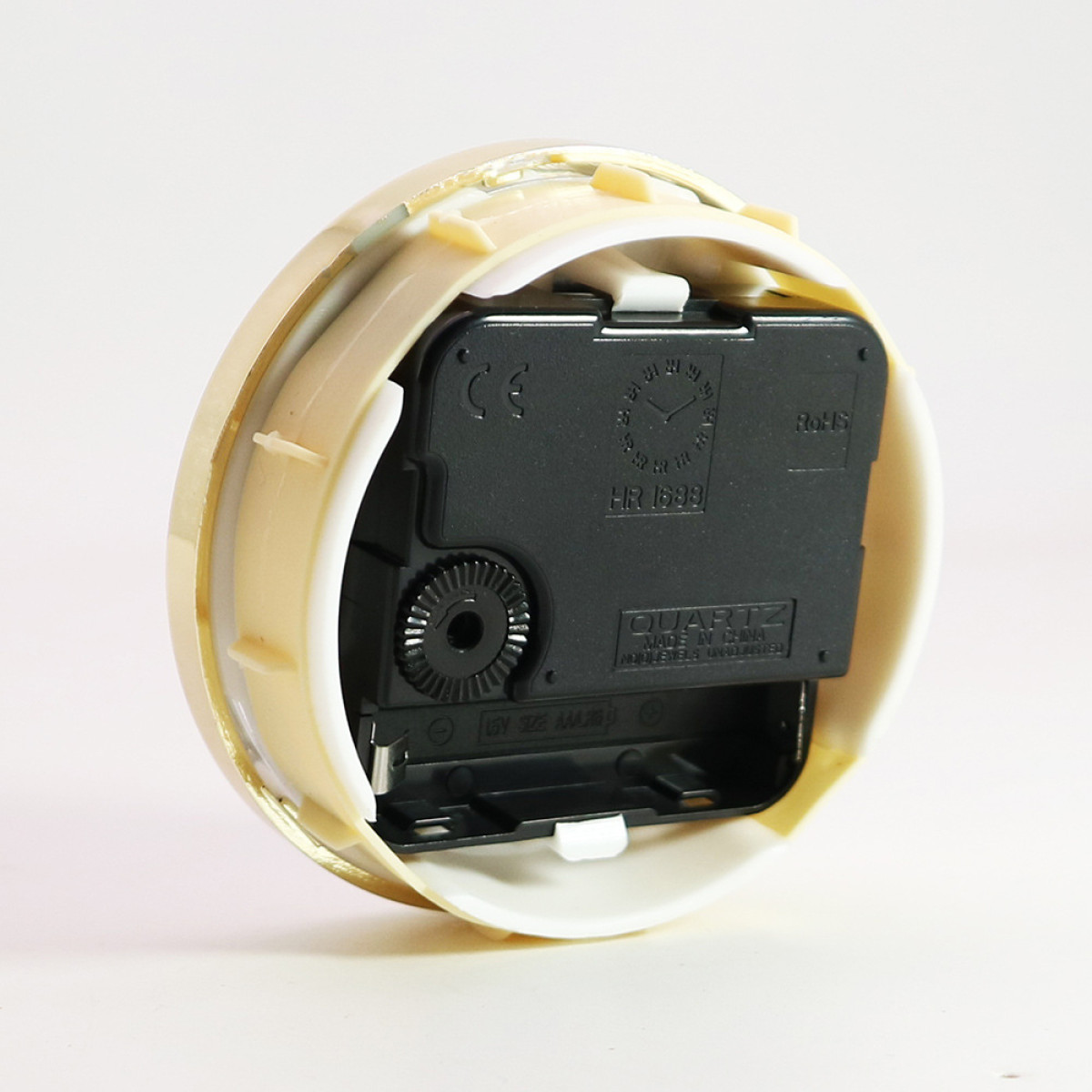 Das Innere einer Uhr mit der Rückseite des Zifferblatts, das den Mechanismus und eine Batterie zeigt.