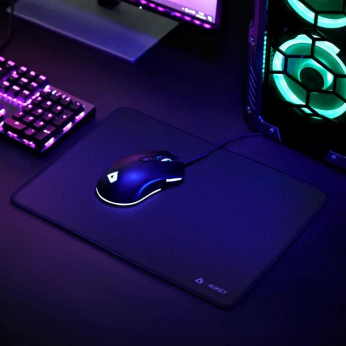 Eine Gaming-Maus auf einem Mauspad, beleuchtet von einem lila Schein. Tastatur und PC sind im Hintergrund sichtbar.