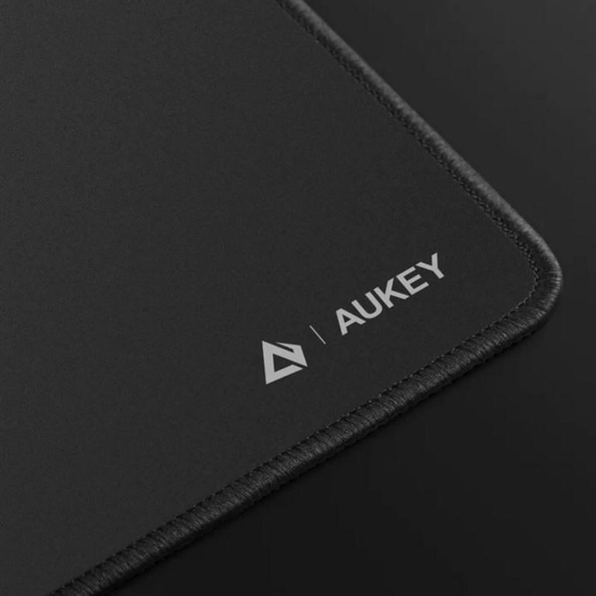 Schwarzes Mauspad mit weißem Aukey-Logo in der Ecke. Schwarze Oberfläche.