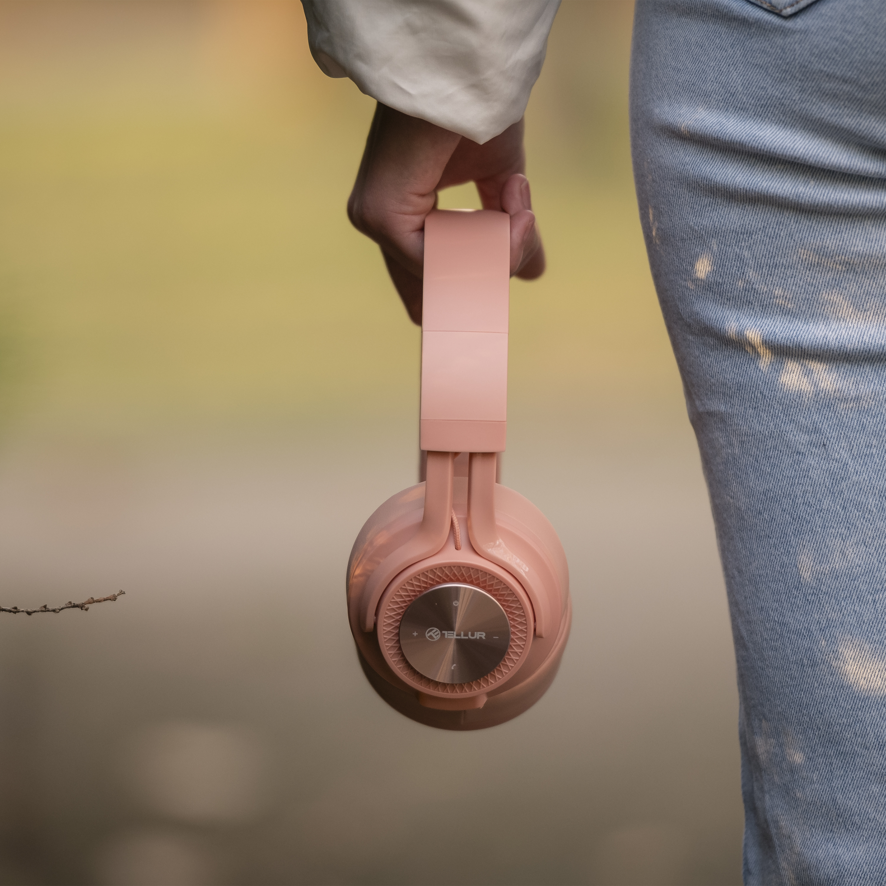 Eine Person hält pinkfarbene Kopfhörer mit metallischer Basis, Nahaufnahme.