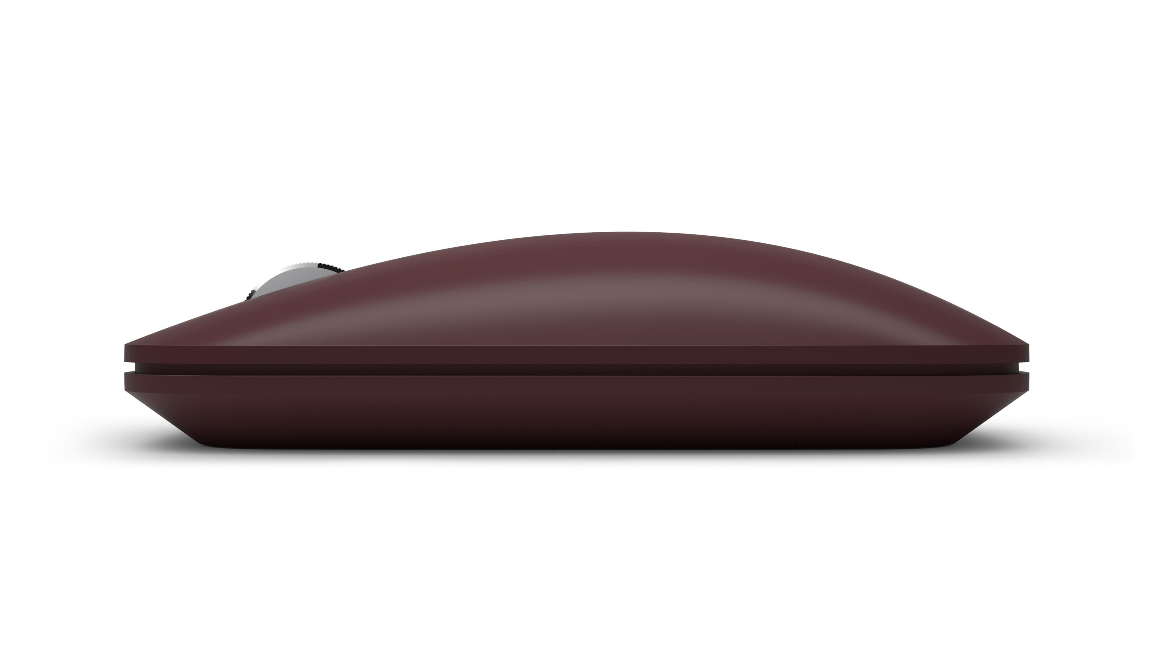 Un mouse wireless marrone con una curva sottile, visto di lato su una superficie bianca.