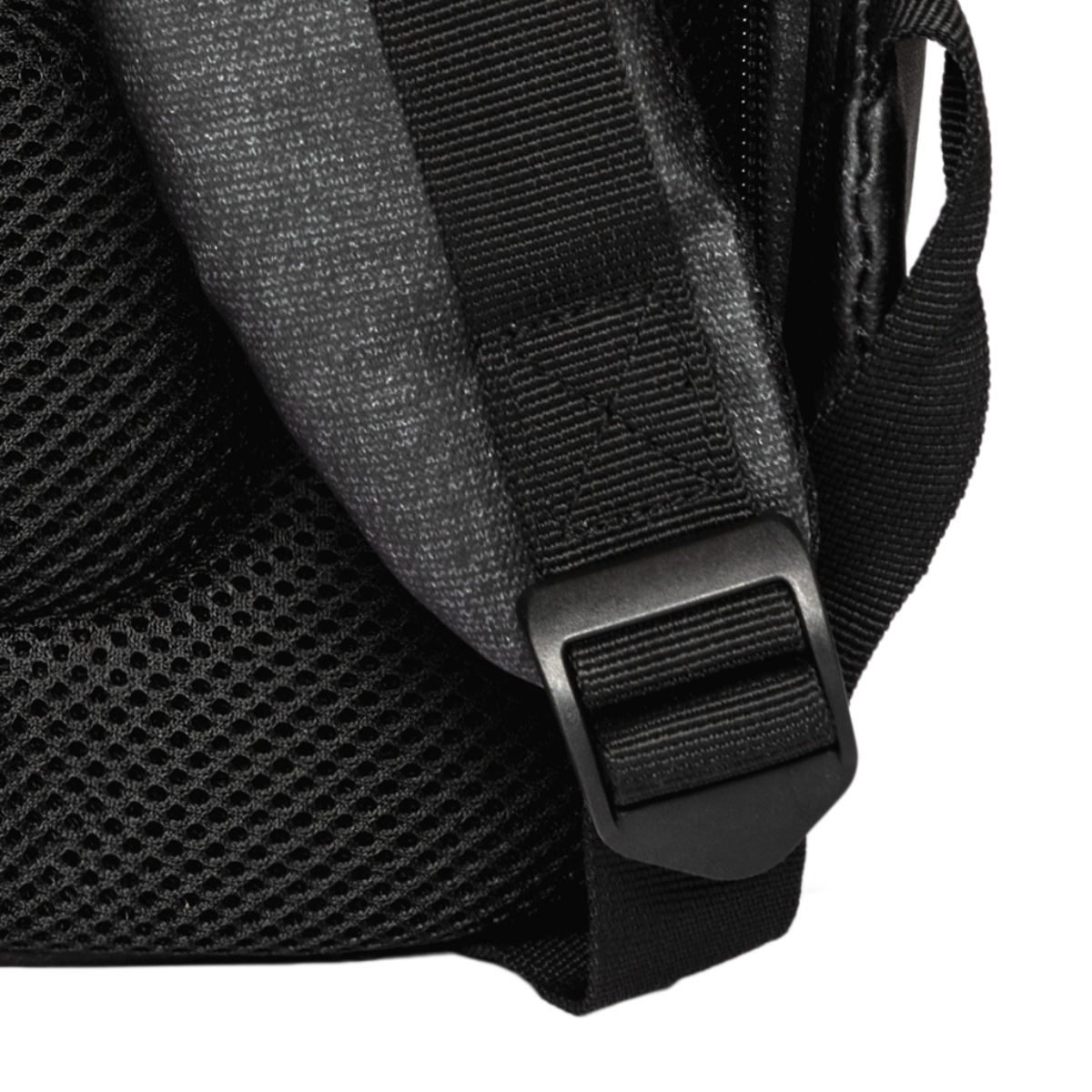 Detalle de mochila negra: hebilla, correa y malla. Tejido texturizado gris y negro.