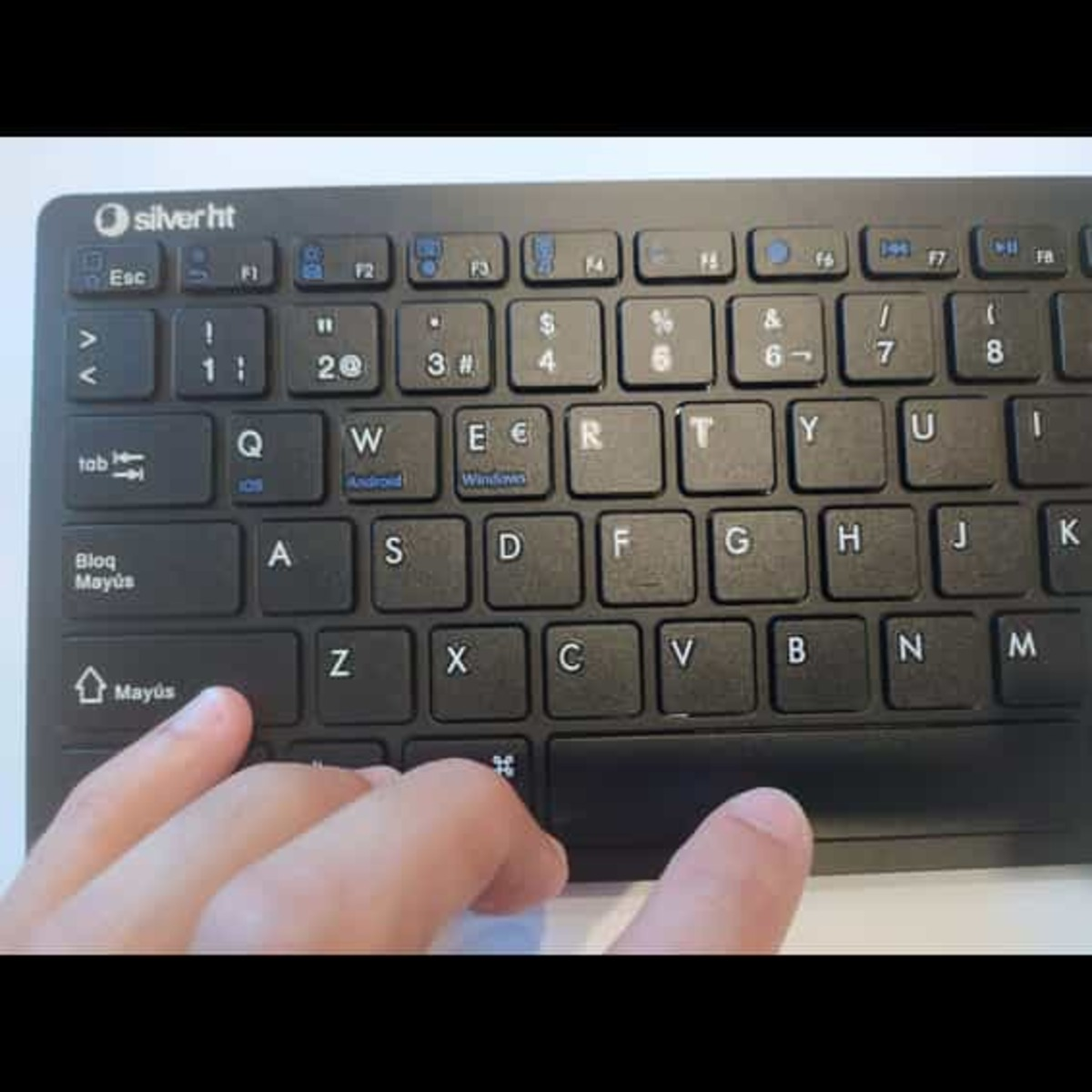 Teclado negro con teclas y dedos en la barra espaciadora.