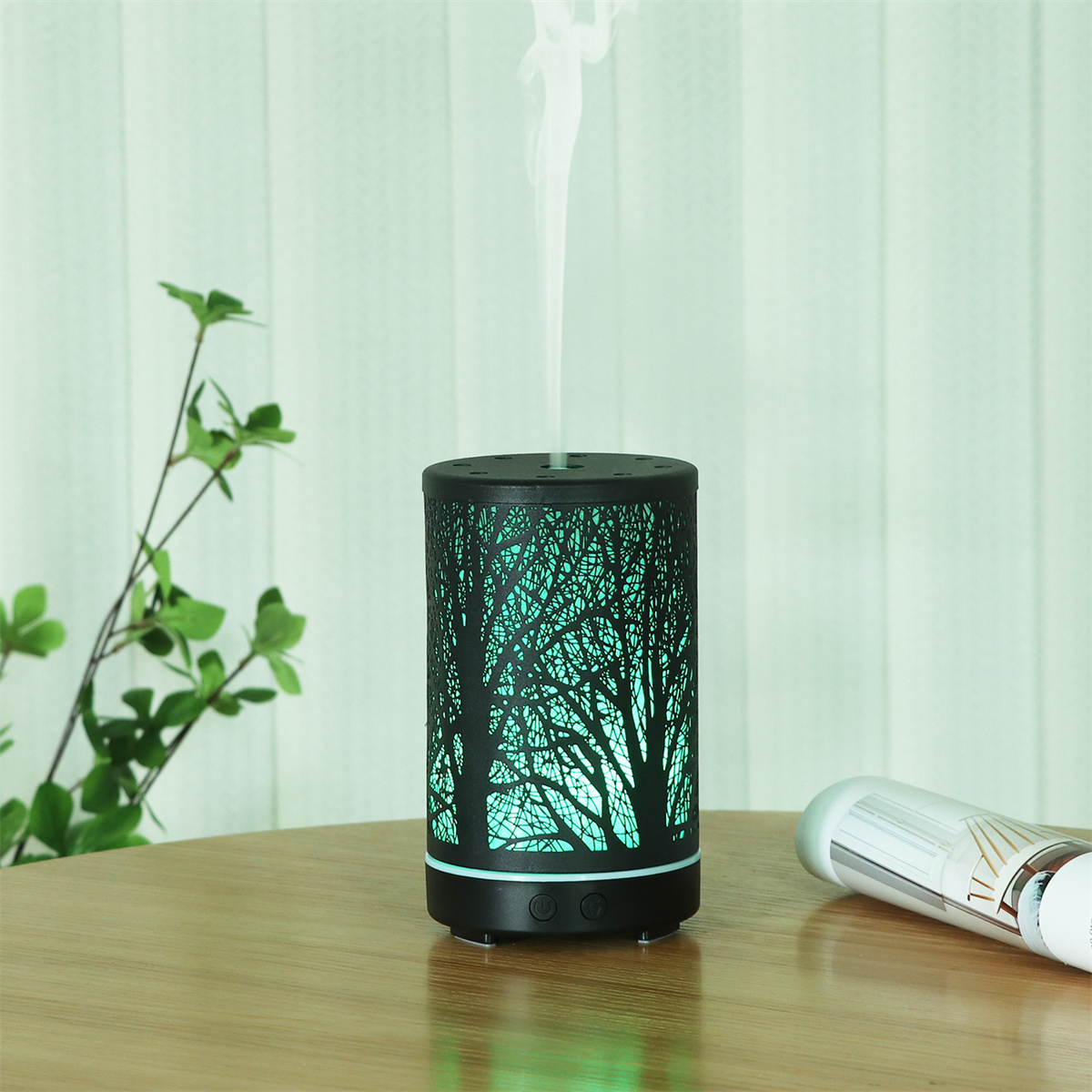 Schwarzer Luftdiffusor mit Baumsilhouetten-Design. Dampf emittierend. Hellgrünes Leuchten.
