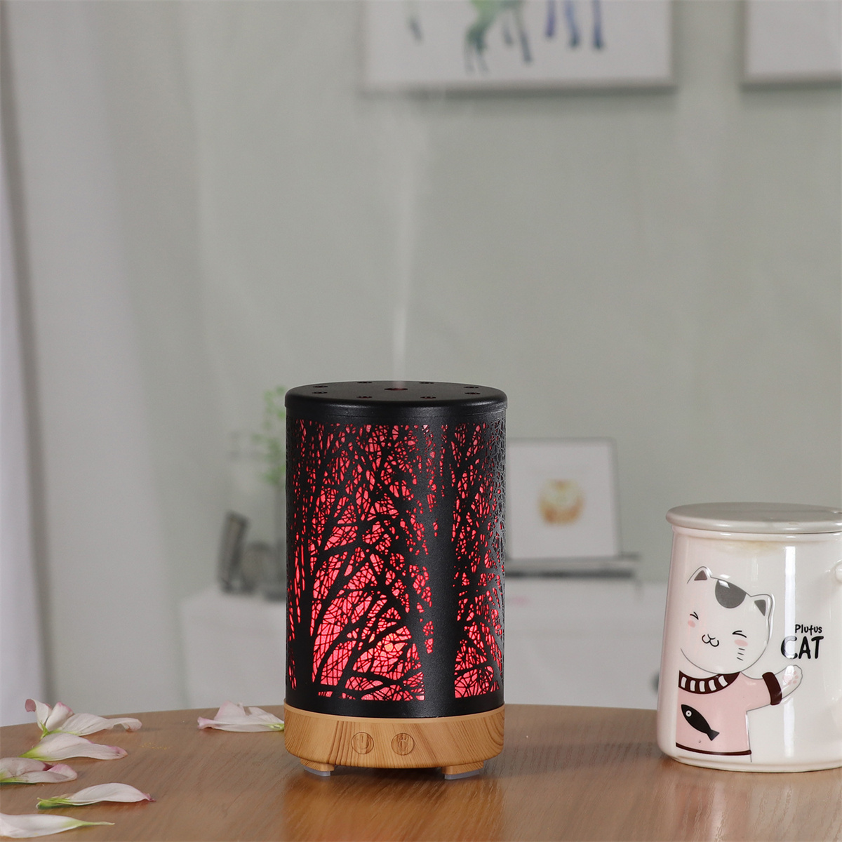 Ein schwarzer und roter Aromatherapie-Diffusor mit Licht, auf einem Tisch neben einer Katze-Keramik-Tasse.