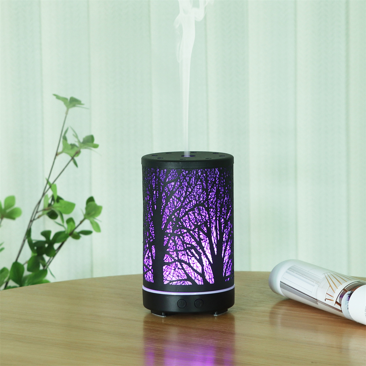 Aromadiffusor mit Baum-Silhouette-Design, der Dampf abgibt, auf einem Tisch platziert.