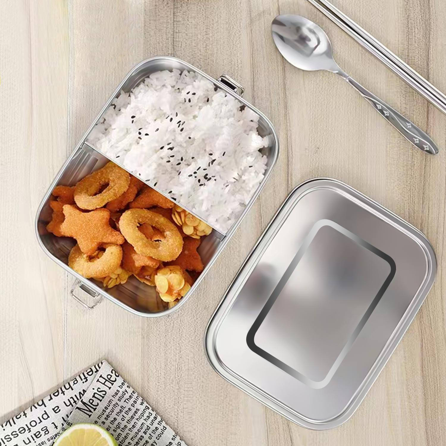Lunchbox mit Reis und gebratenem Essen. Löffel und Essstäbchen auf dem Tisch.
