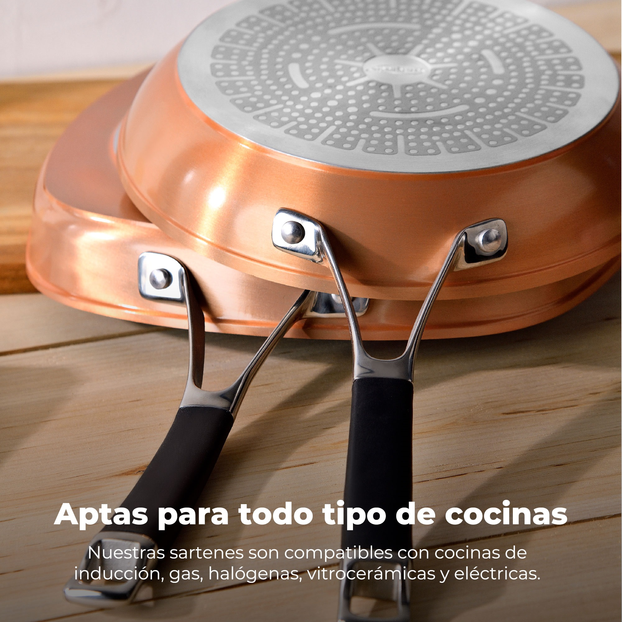 Dos sartenes color cobre, una encima de la otra, con mangos negros. El fondo es una superficie de madera.