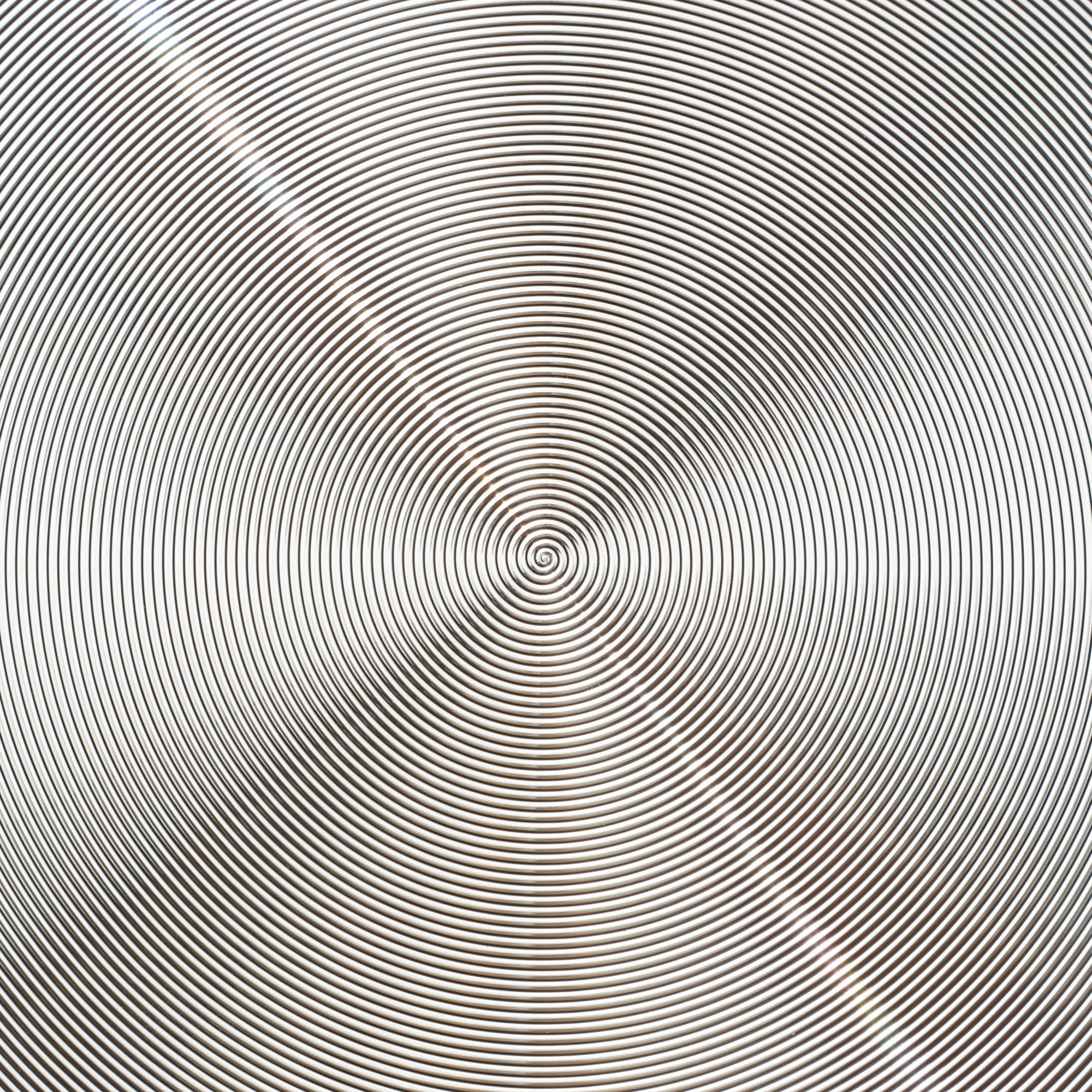 Un patrón circular, un diseño en espiral con círculos concéntricos, con algo de reflexión de la luz.