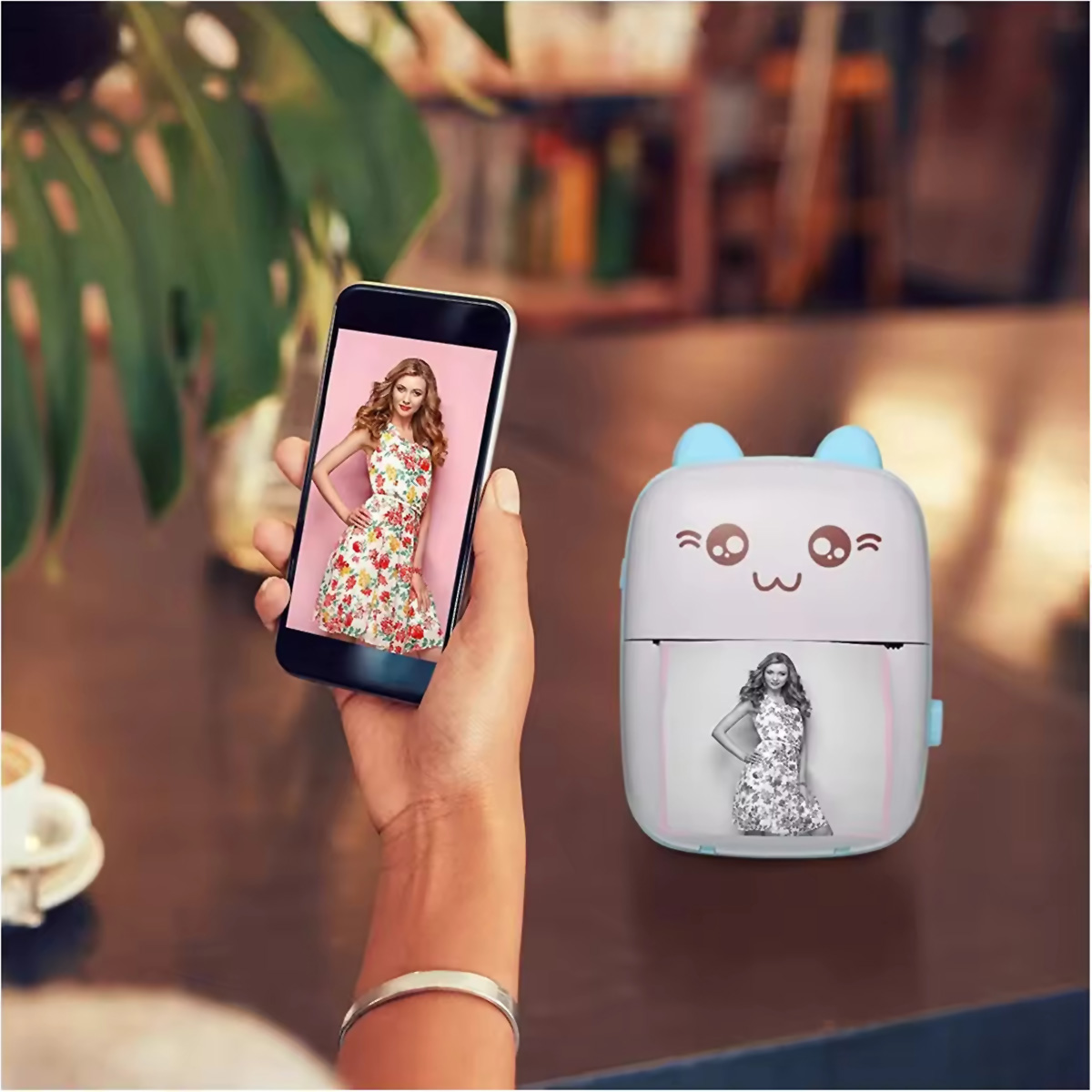 Una mujer usa un teléfono para imprimir una foto, una pequeña impresora está junto a ella en una mesa.