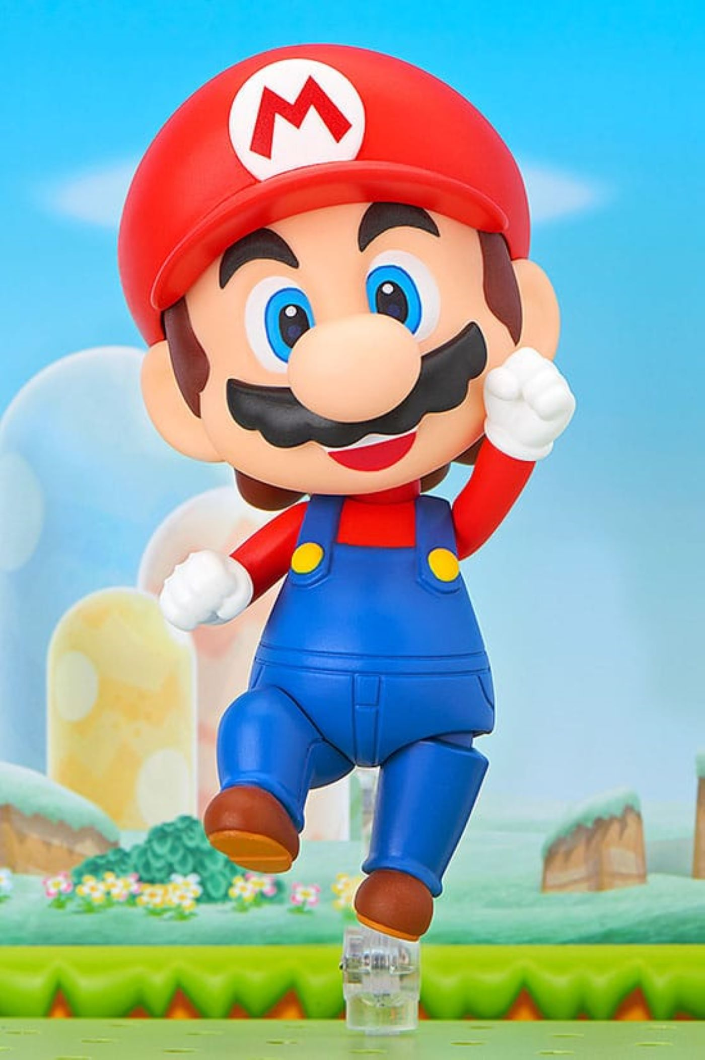 Eine Mario-Figur in Sprunghaltung. Er trägt eine rote Kappe, blaue Latzhosen und braune Schuhe, auf einer grünen Basis.