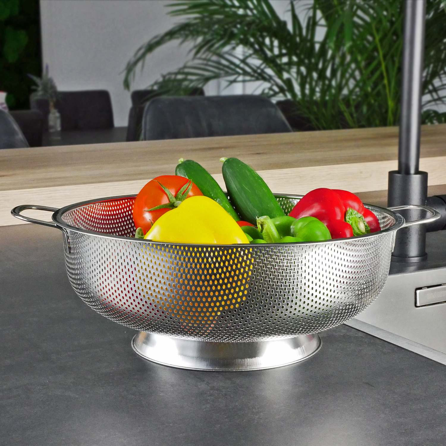 Ein Metall-Gemüsesieb gefüllt mit frischem Gemüse: Tomaten, Gurken, Paprika.