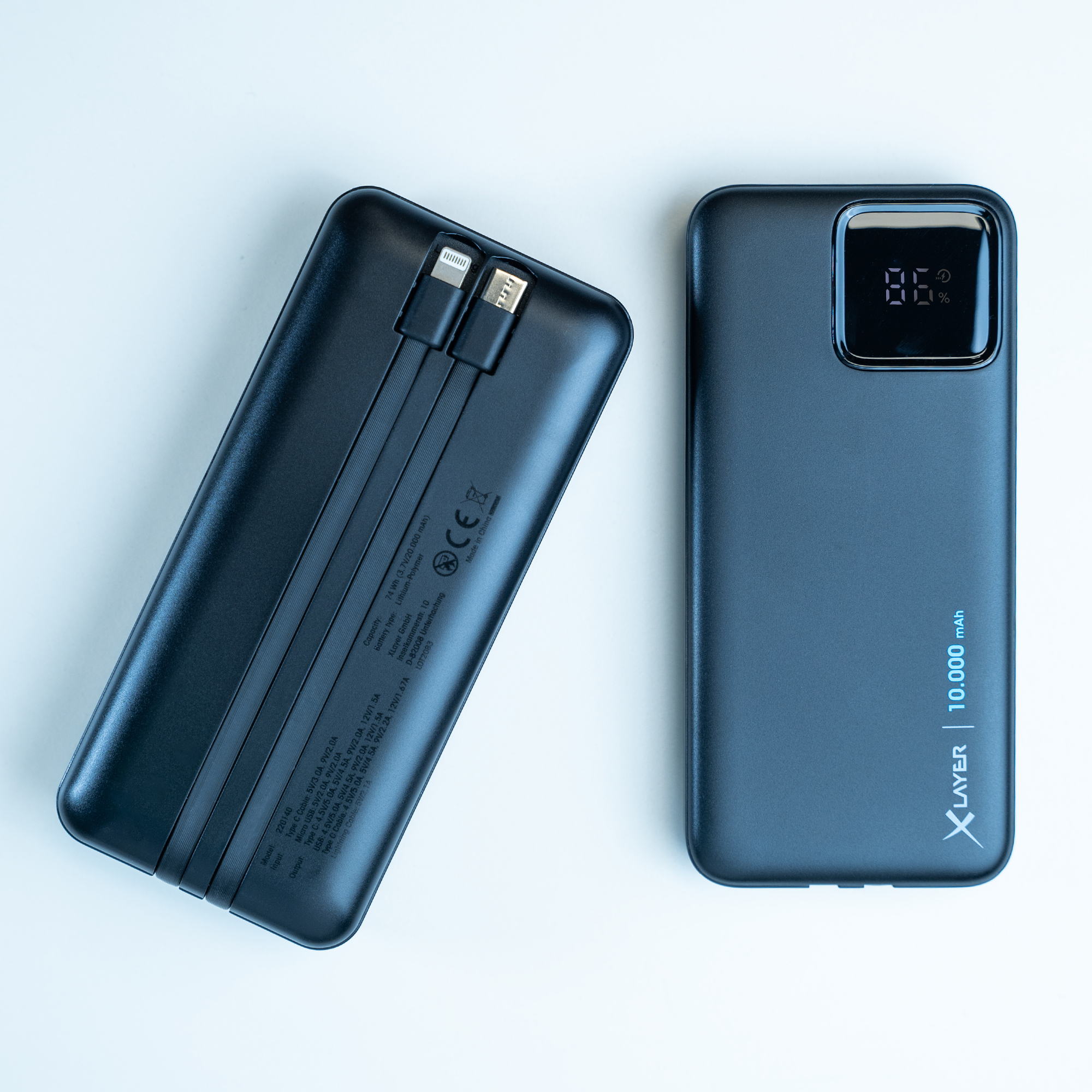 Zwei schwarze Powerbanks auf weißem Untergrund. Eine mit Bildschirm, 86%. Die andere mit Lightning- und USB-C-Anschlüssen.