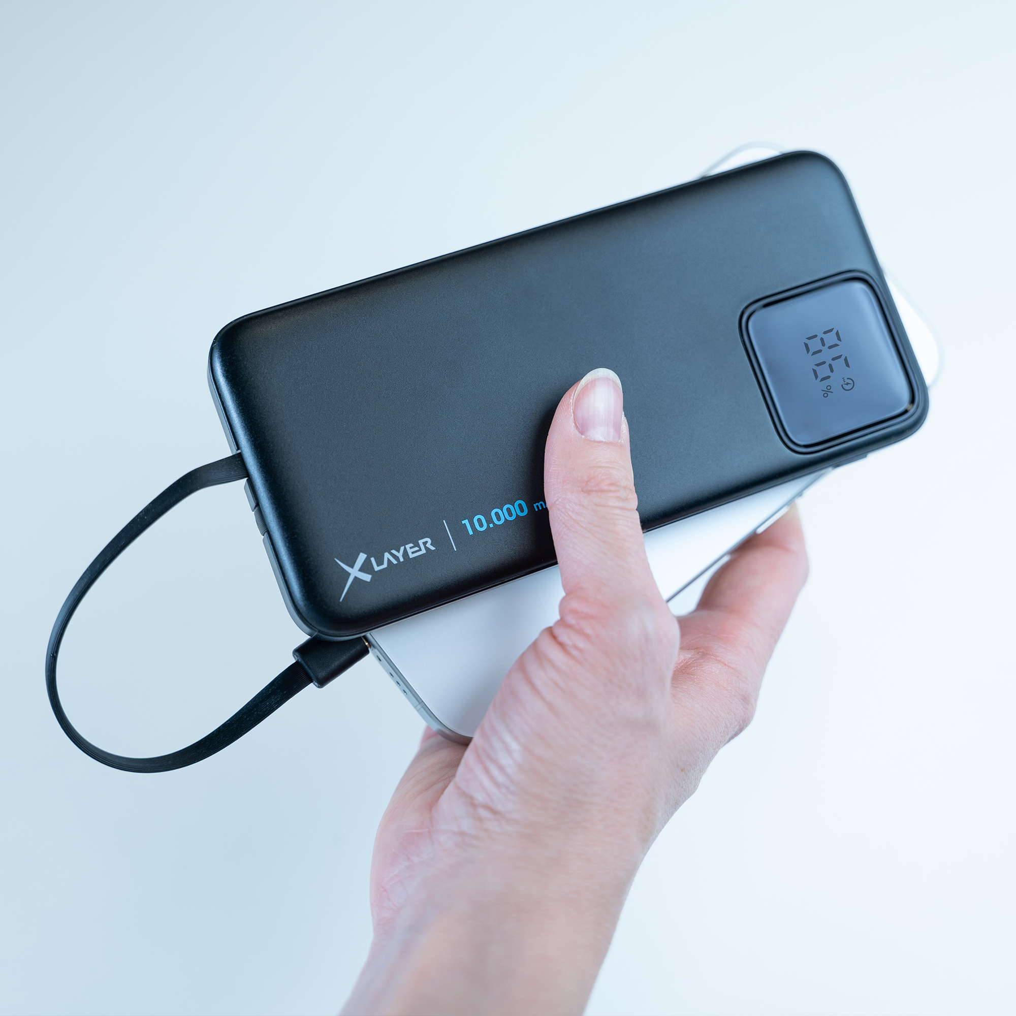 Eine schwarze Powerbank mit digitaler Anzeige und einem Ladekabel, das an ein Telefon angeschlossen ist.