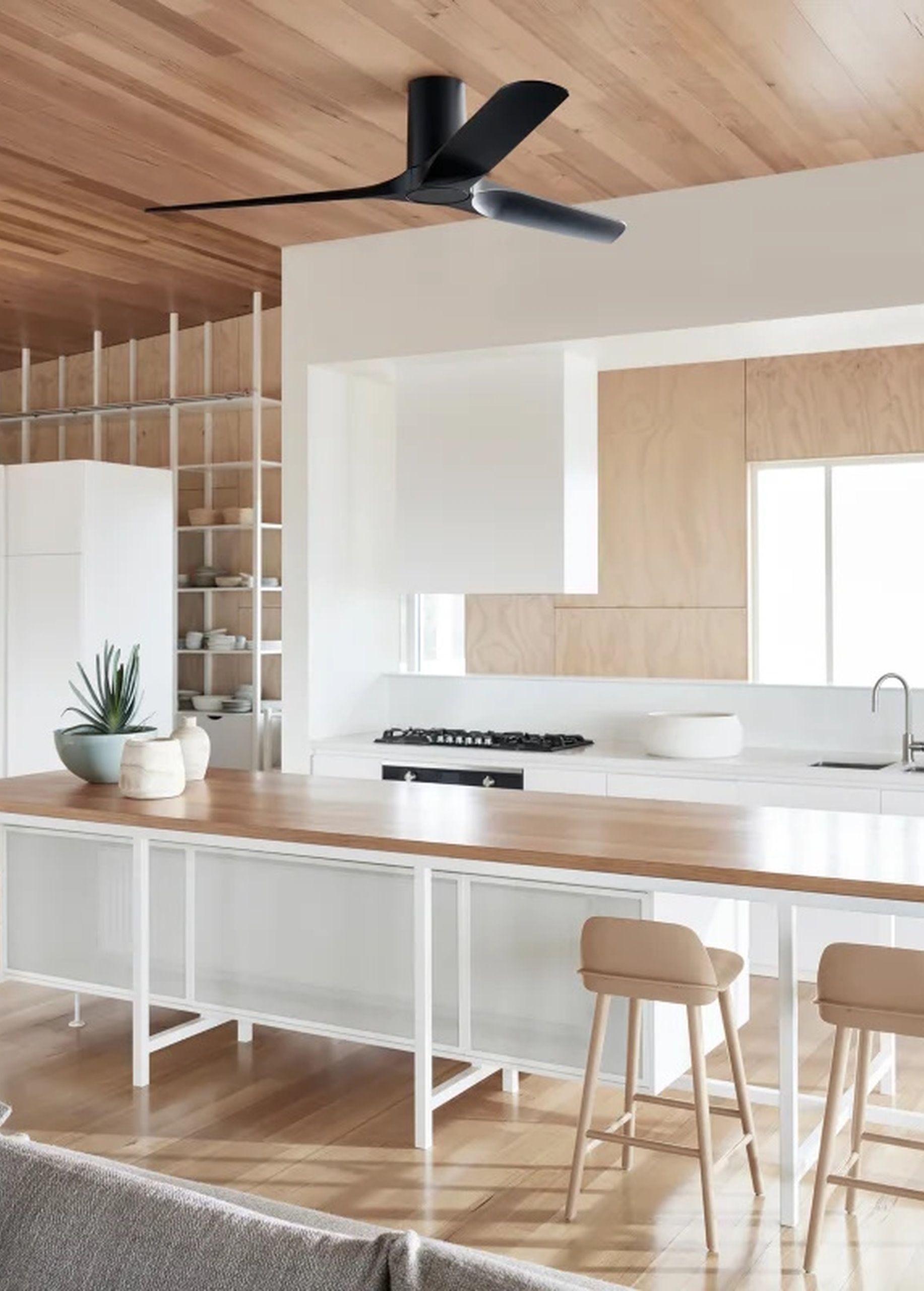Cucina moderna con ventilatore a soffitto, soffitto in legno, pareti bianche e un'isola cucina lunga con sgabelli.