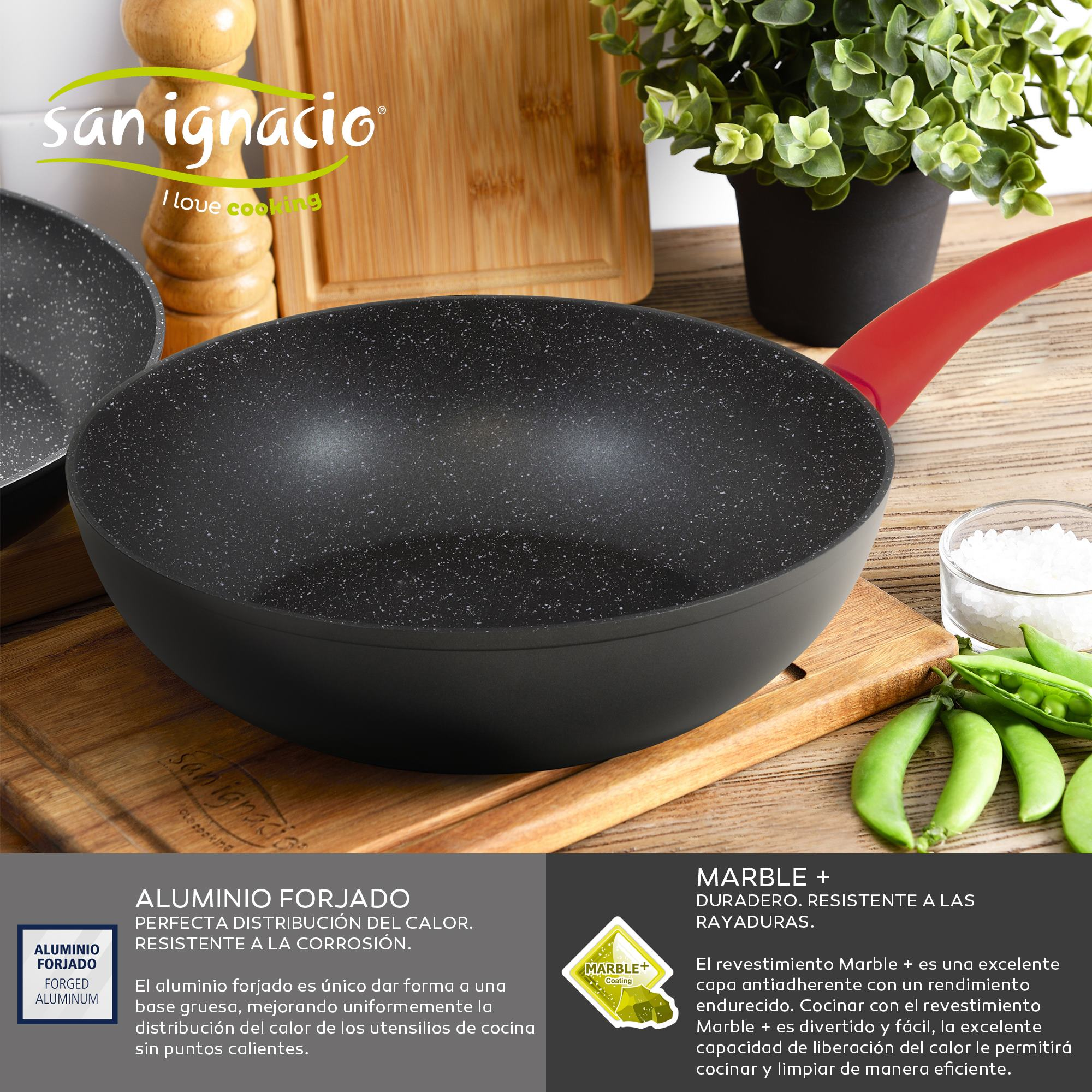 Una sartén negra sobre una tabla de madera con ingredientes, un mango rojo y el logo 'San Ignacio'.
