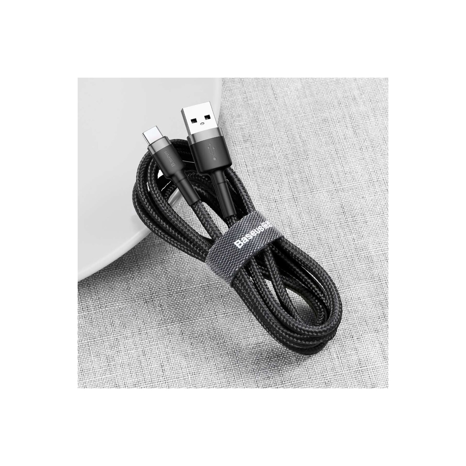 Czarny kabel USB-C do USB, zwinięty na białej powierzchni. Kabel ma etykietę Baseus.