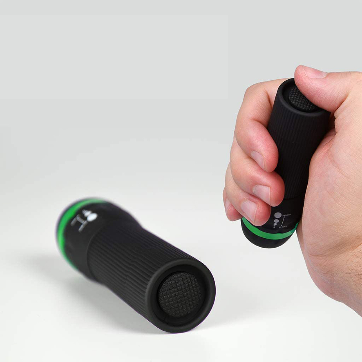 Zwei schwarze Taschenlampen, eine in der Hand, mit grünen Akzenten.