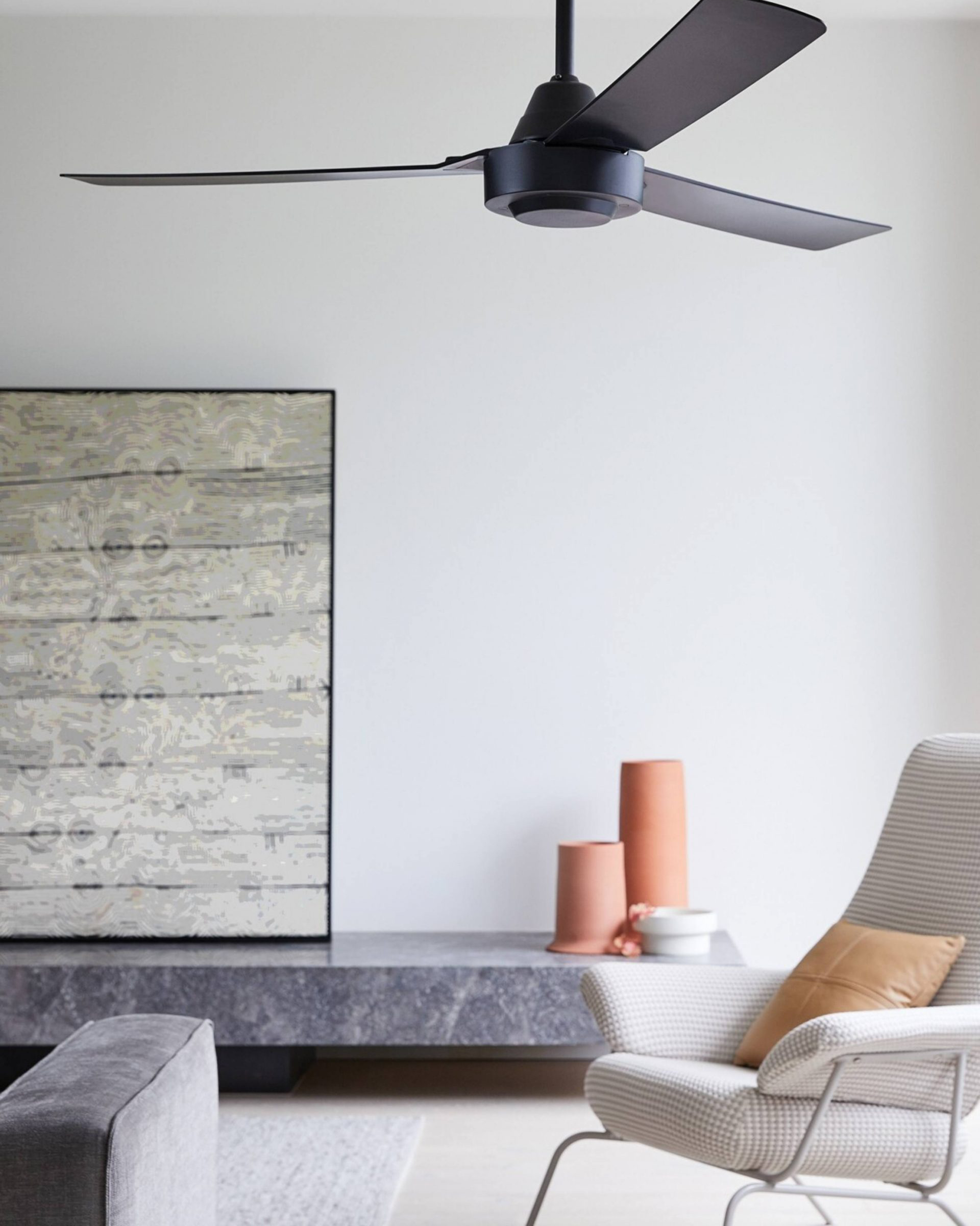 Ein Raum mit Deckenventilator, Kunstwerk und Stuhl. Neutrale Farben, modernes Design.