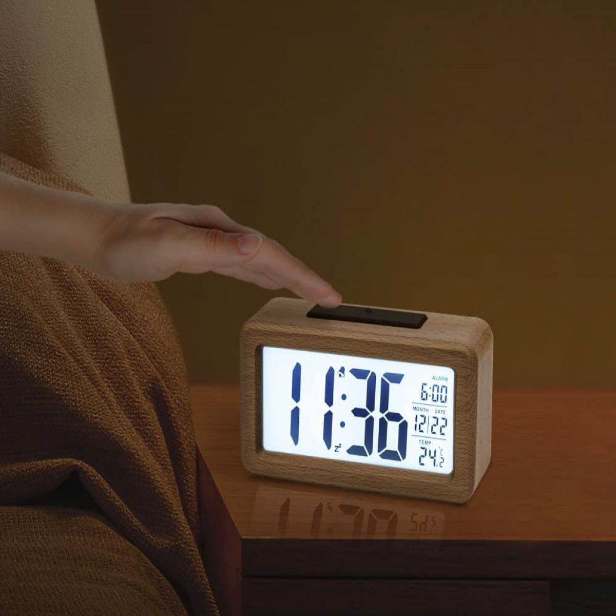 Wecker aus Holz mit der Anzeige 11:36. Eine Hand greift nach der Uhr.