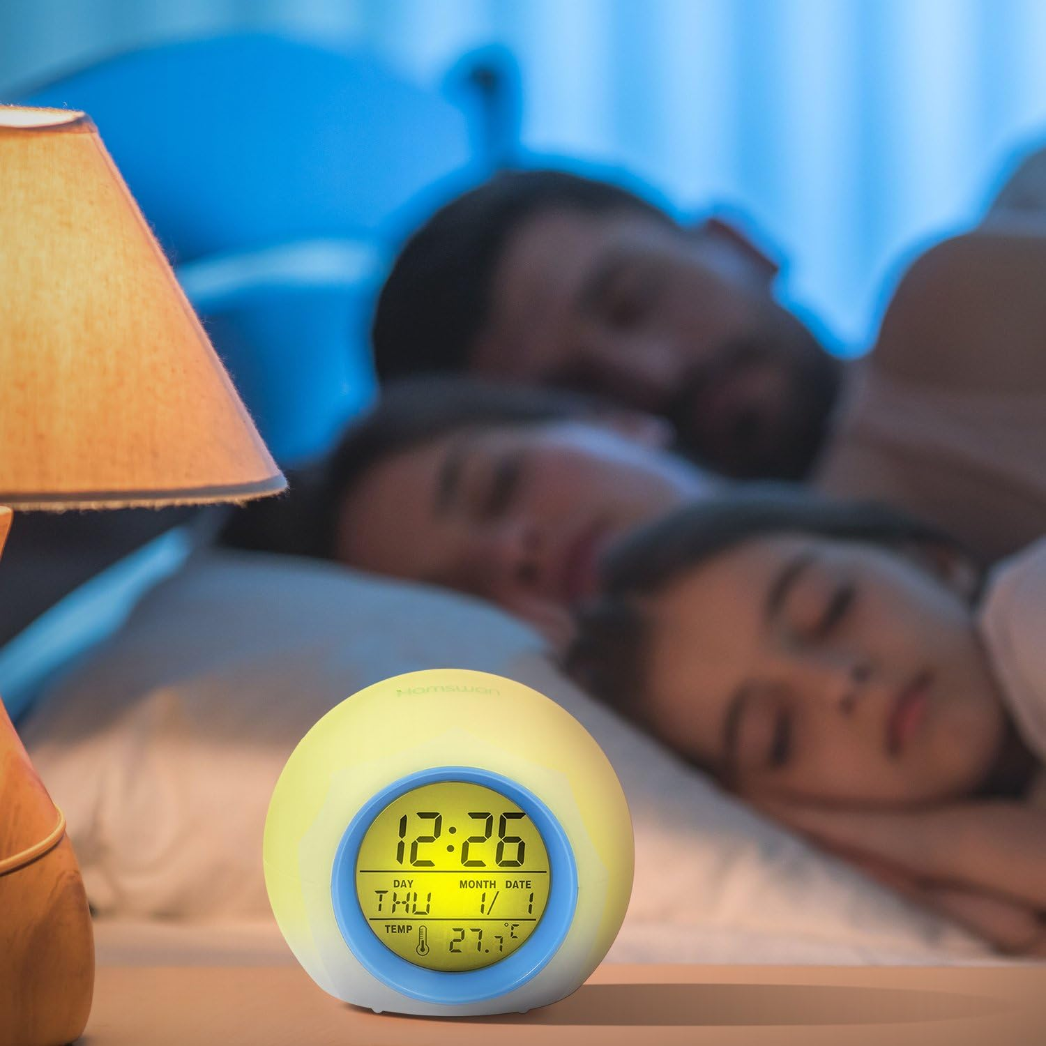 Ein beleuchteter Wecker auf einem Nachttisch, mit einer Familie, die im Hintergrund schläft.