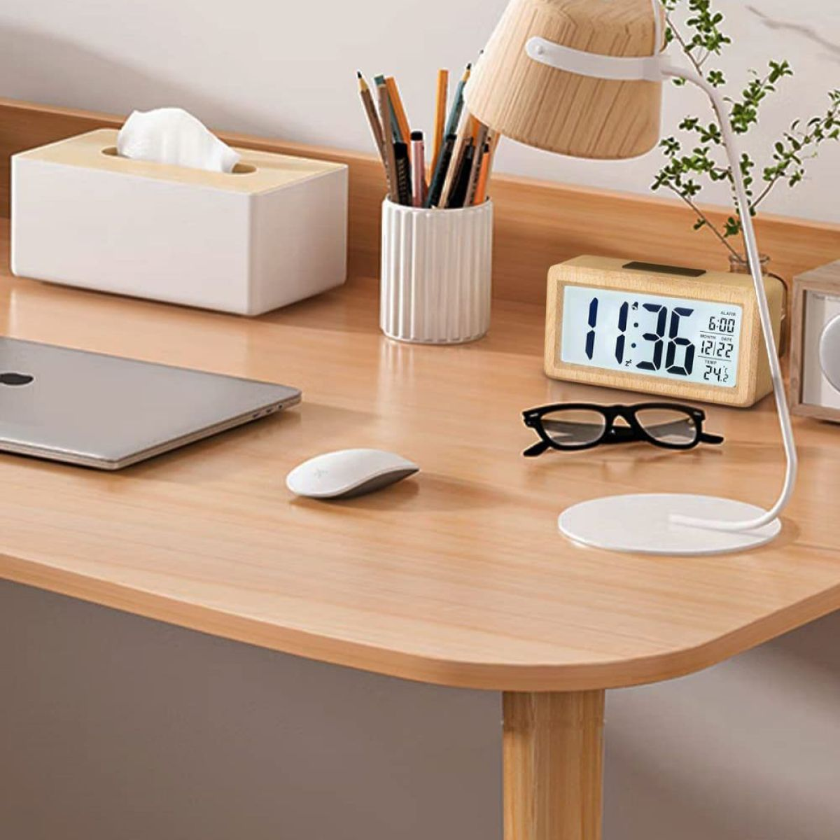 Ein Schreibtisch mit Uhr, Brille, Maus und Lampe.