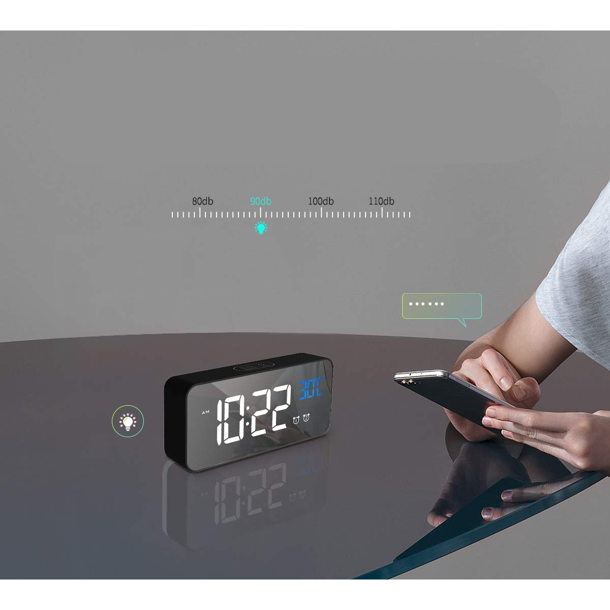 Ein schwarzer Wecker mit der Anzeige 10:22, mit Telefon und Sprechblase. Grauer Hintergrund.