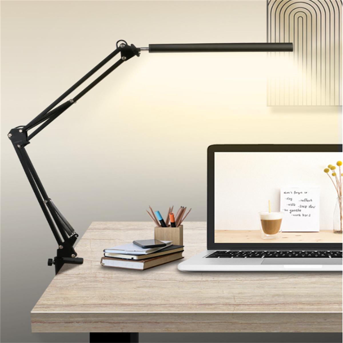 Schwarze Schreibtischlampe über einem Schreibtisch mit Laptop, Notizbüchern und Stiften.