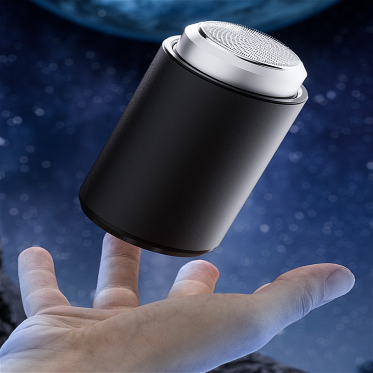 Eine Hand hält einen kleinen schwarzen elektrischen Rasierer vor einem verschwommenen Weltraumhintergrund.