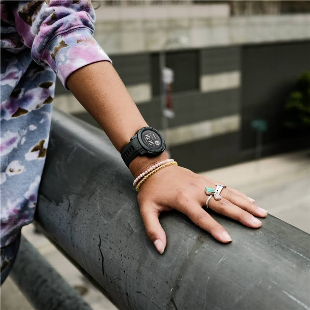 Das Handgelenk einer Person mit einer schwarzen Uhr und Armbändern.