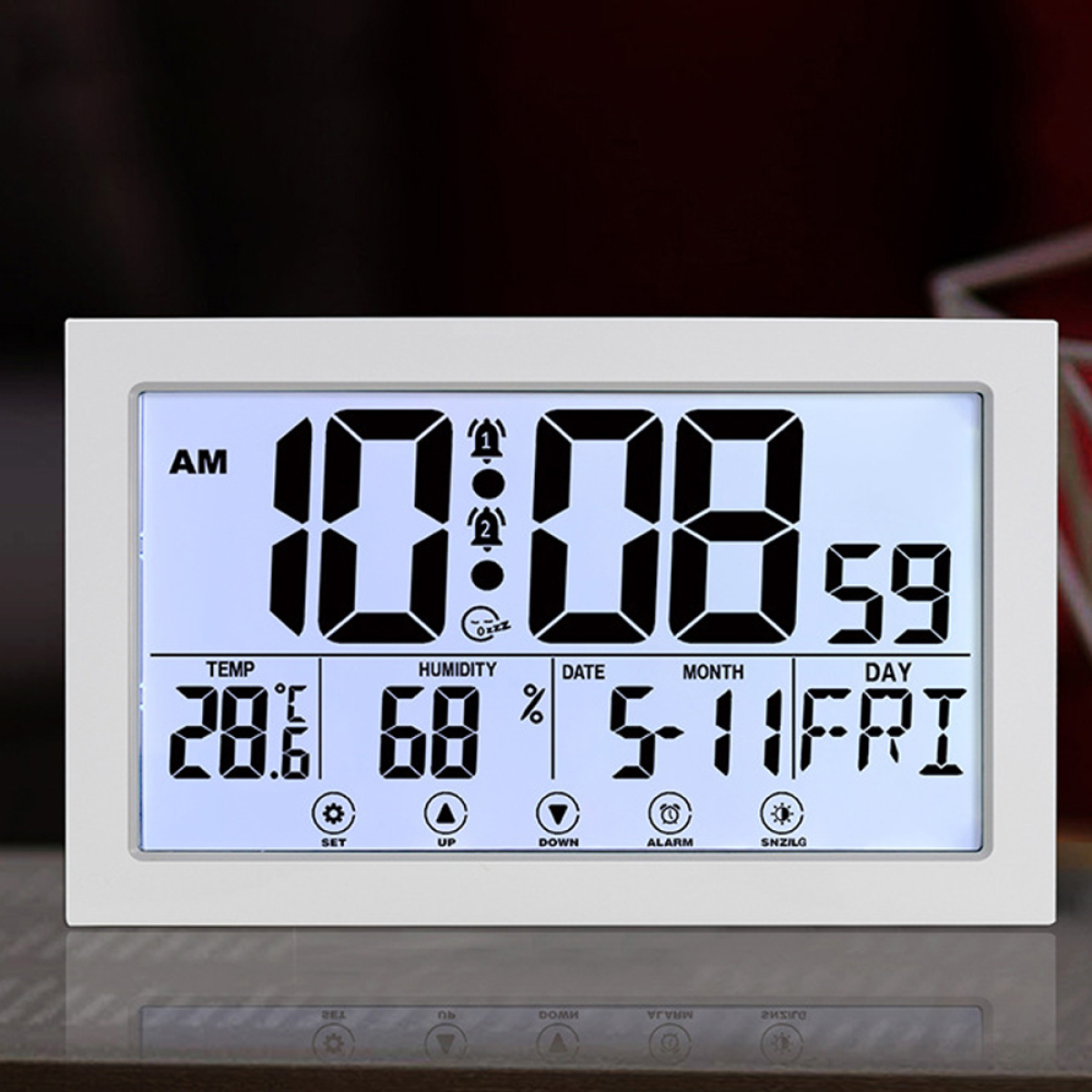 Eine Digitaluhr zeigt Zeit, Temperatur, Luftfeuchtigkeit, Datum und Wochentag auf weißem Hintergrund.