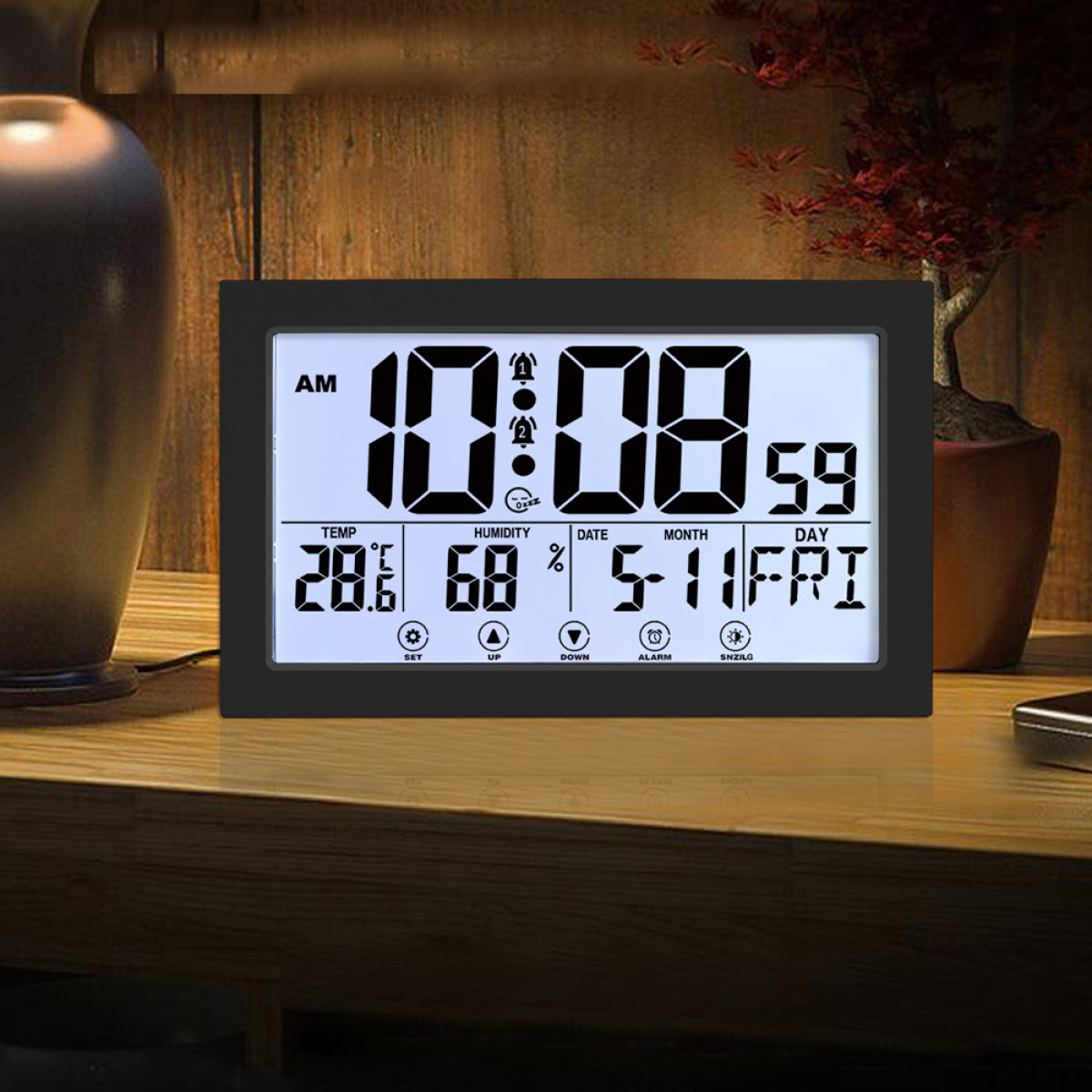 Digitaluhr mit Zeit, Temperatur, Luftfeuchtigkeit, Datum und Tag. Sie steht auf Holz.