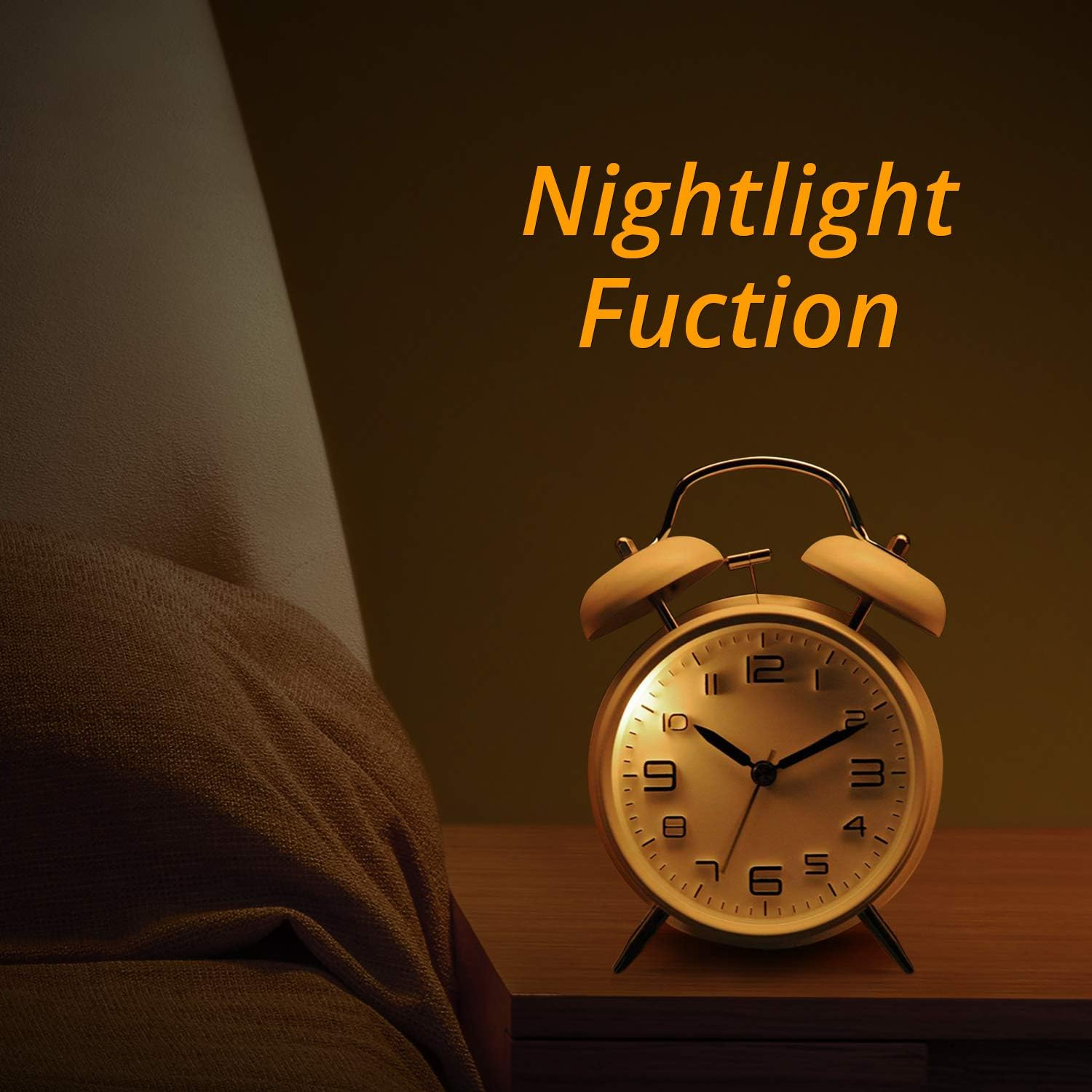 Ein goldfarbener Wecker im alten Stil auf einem Holztisch. Die Uhr befindet sich neben einem Bett mit einer braunen Decke.