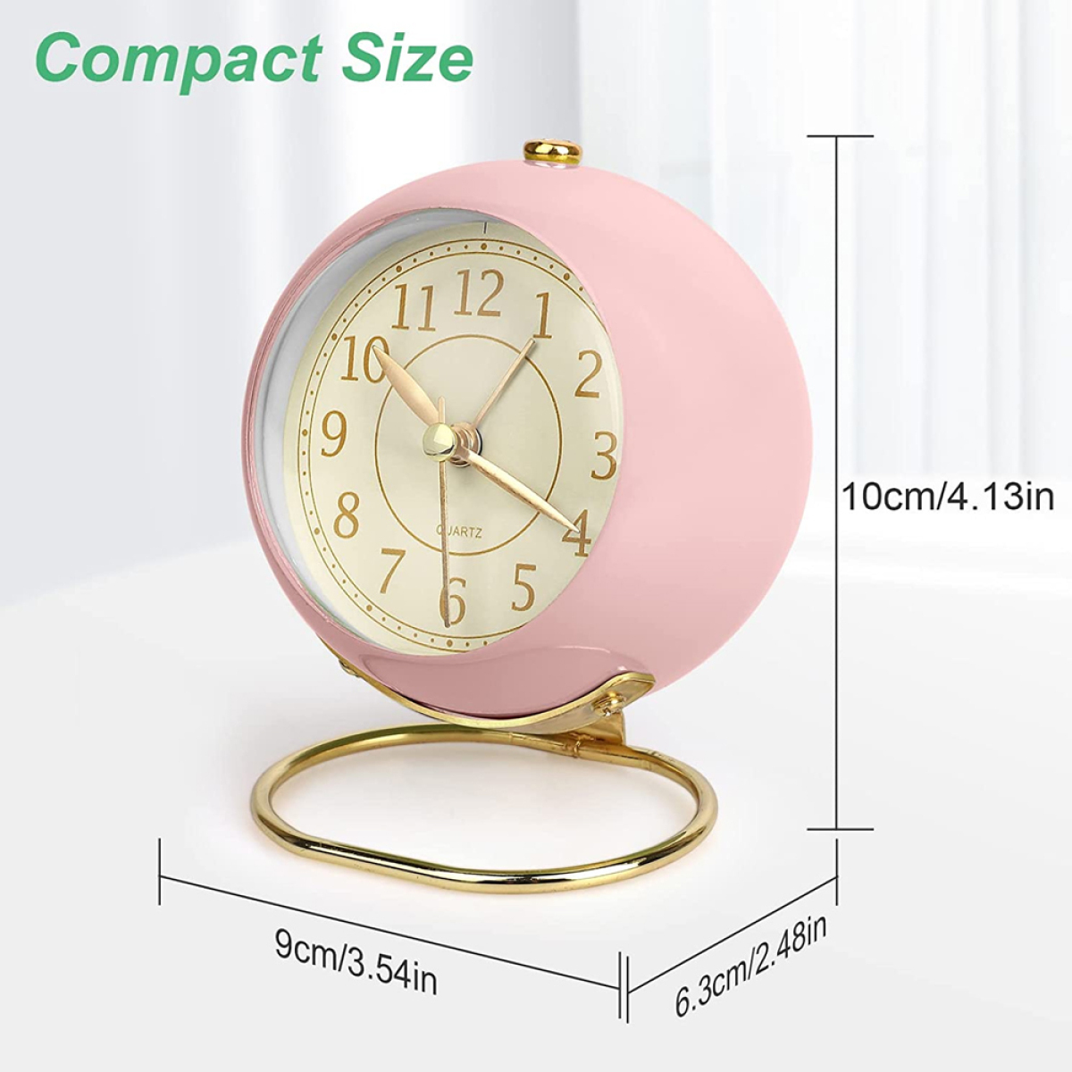 Ein rosa, runder Wecker auf einem goldenen Ständer mit Abmessungen in cm und Zoll.