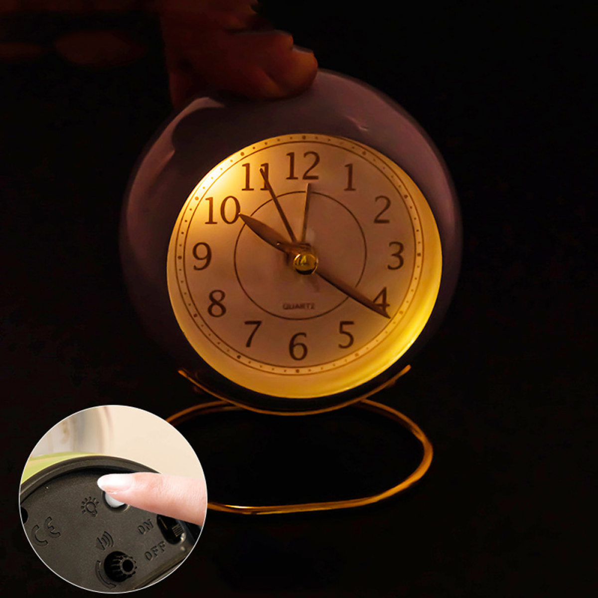Runde Uhr mit beleuchtetem Zifferblatt, vor dunklem Hintergrund. Eine Hand stellt die Einstellungen ein.