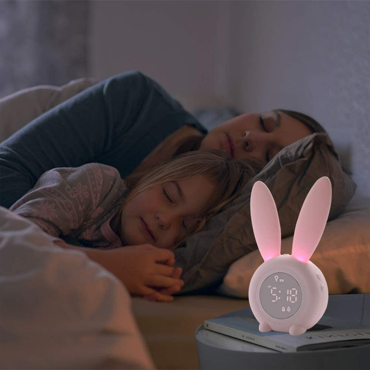 Ein Kind und eine Frau schlafen im Bett, mit einer Hasen-Uhr auf dem Nachttisch.